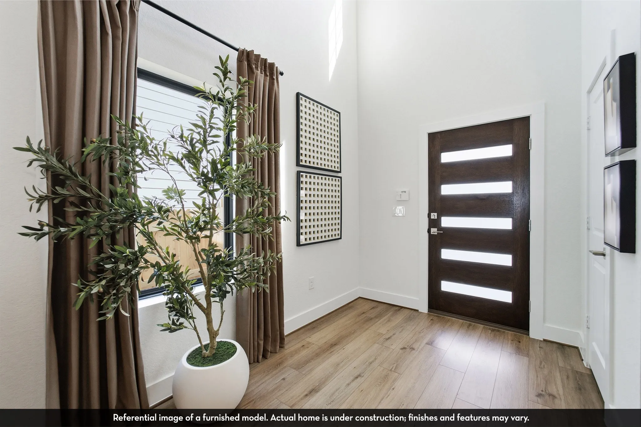 Wood-finish flooring throughout, modern entry door with frosted glass panels, and abundant natural light