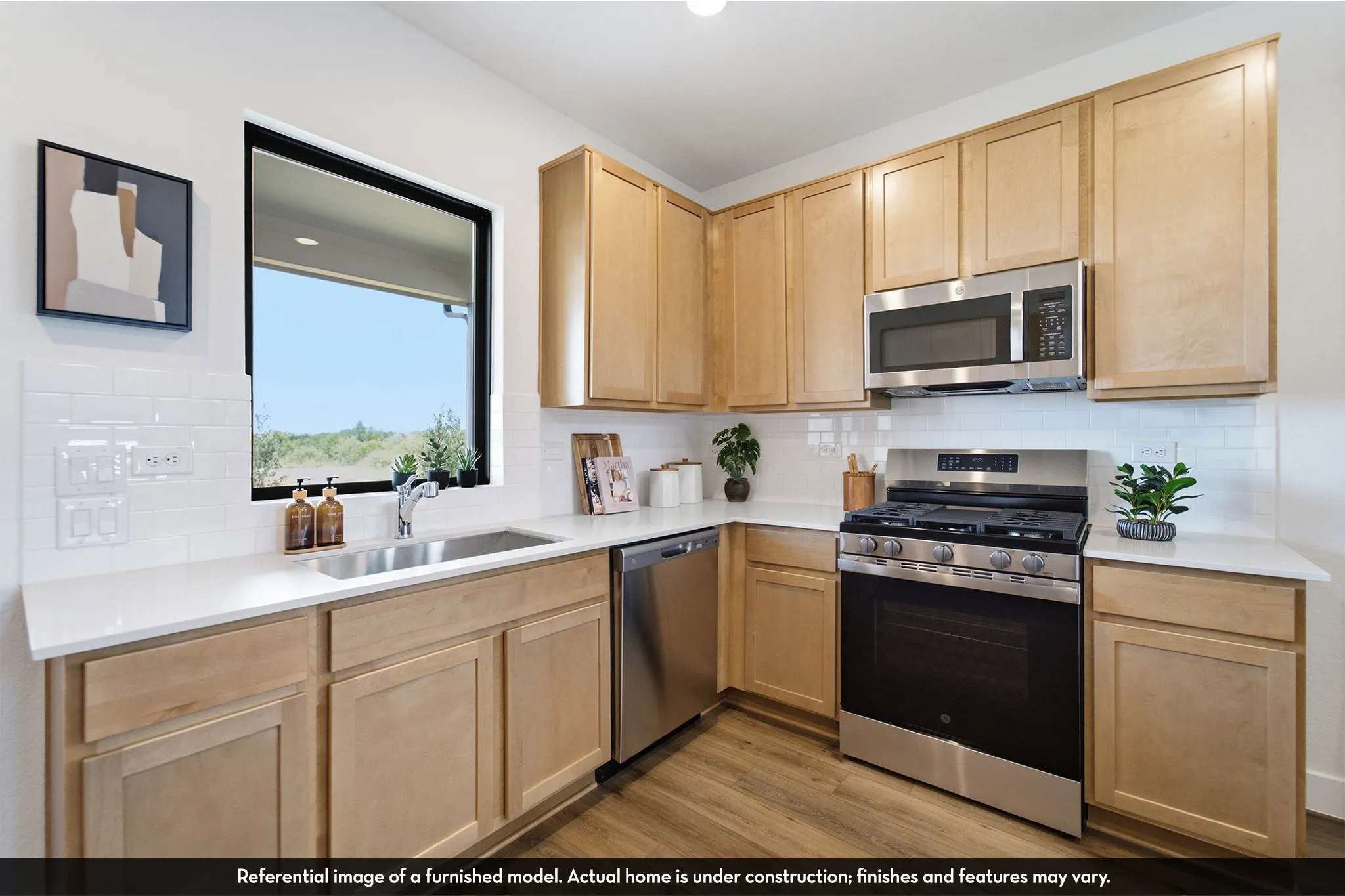 Light wood-finish cabinetry, stainless steel appliances, white subway tile backsplash, white countertops, and a window above the sink