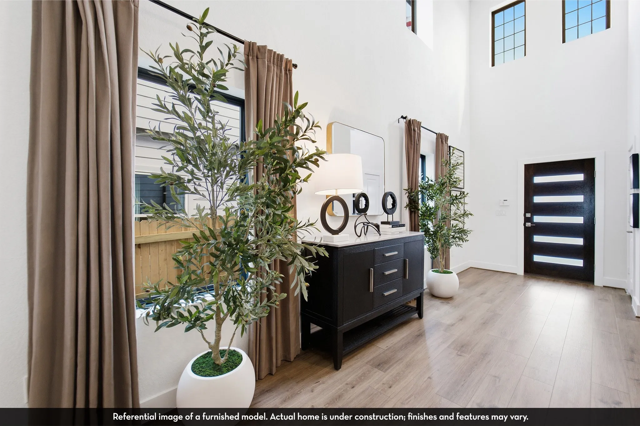 Two-story entry with high ceilings, contemporary front door, wood-finish flooring, and transom windows