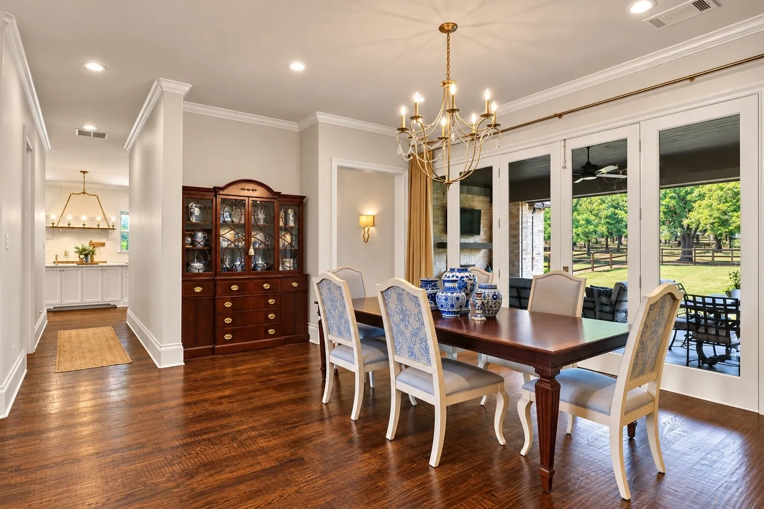 Hardwood flooring, crown molding, double French doors, recessed lighting, and an ornate brass chandelier