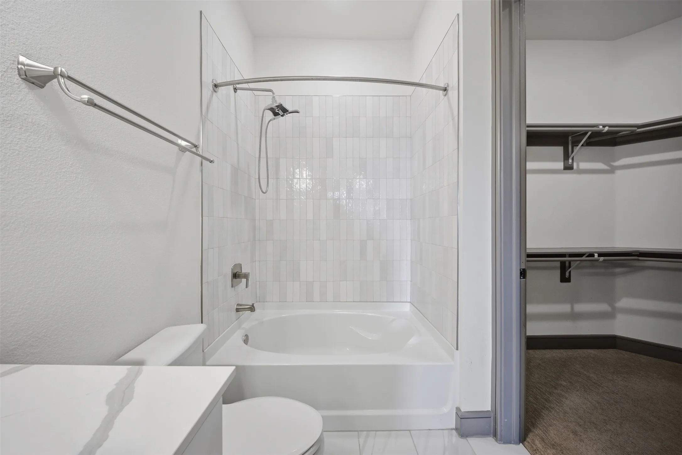 Bathtub with tiled surround, shower fixture, and curved shower rod