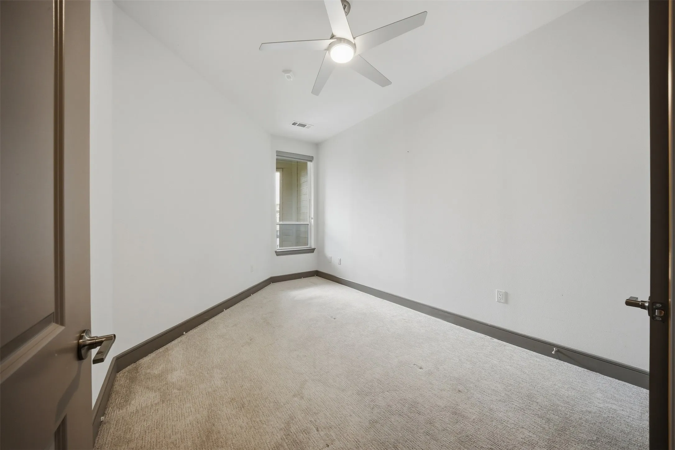 Neutral wall paint with carpet flooring, a ceiling fan with integrated lighting, and a window with blinds