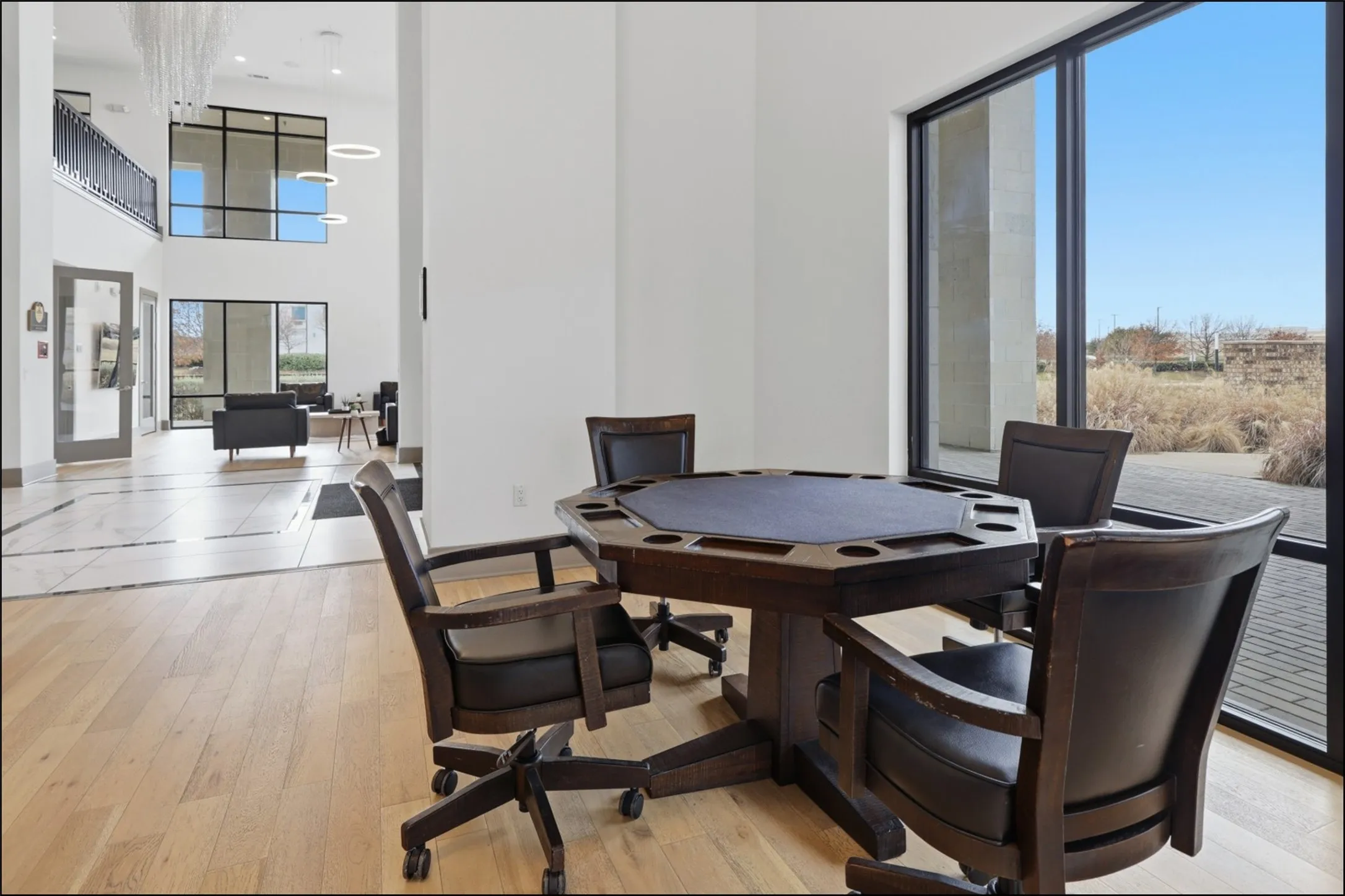 Expansive window wall, light wood-finish flooring, and high ceilings with upper-level architectural details