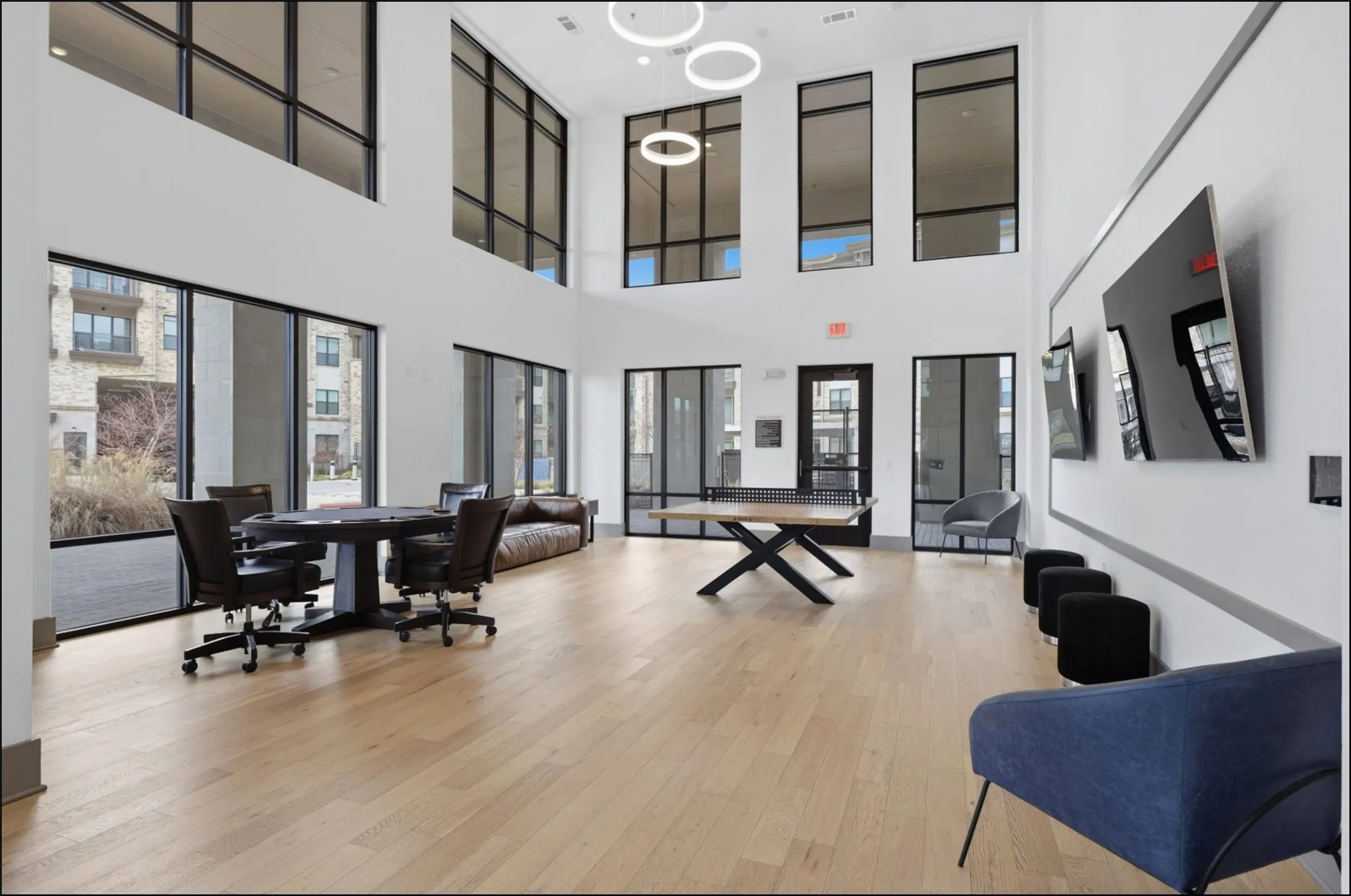 Spacious common area featuring light wood-finish flooring, high ceilings, and expansive windows