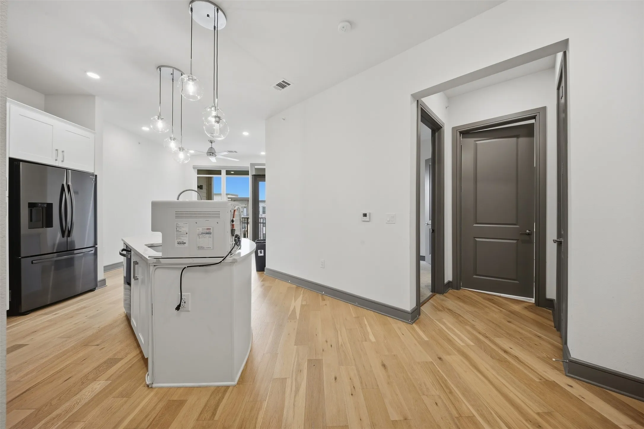 Kitchen island with white countertop, recessed lighting, wood-finish flooring, and stainless steel refrigerator