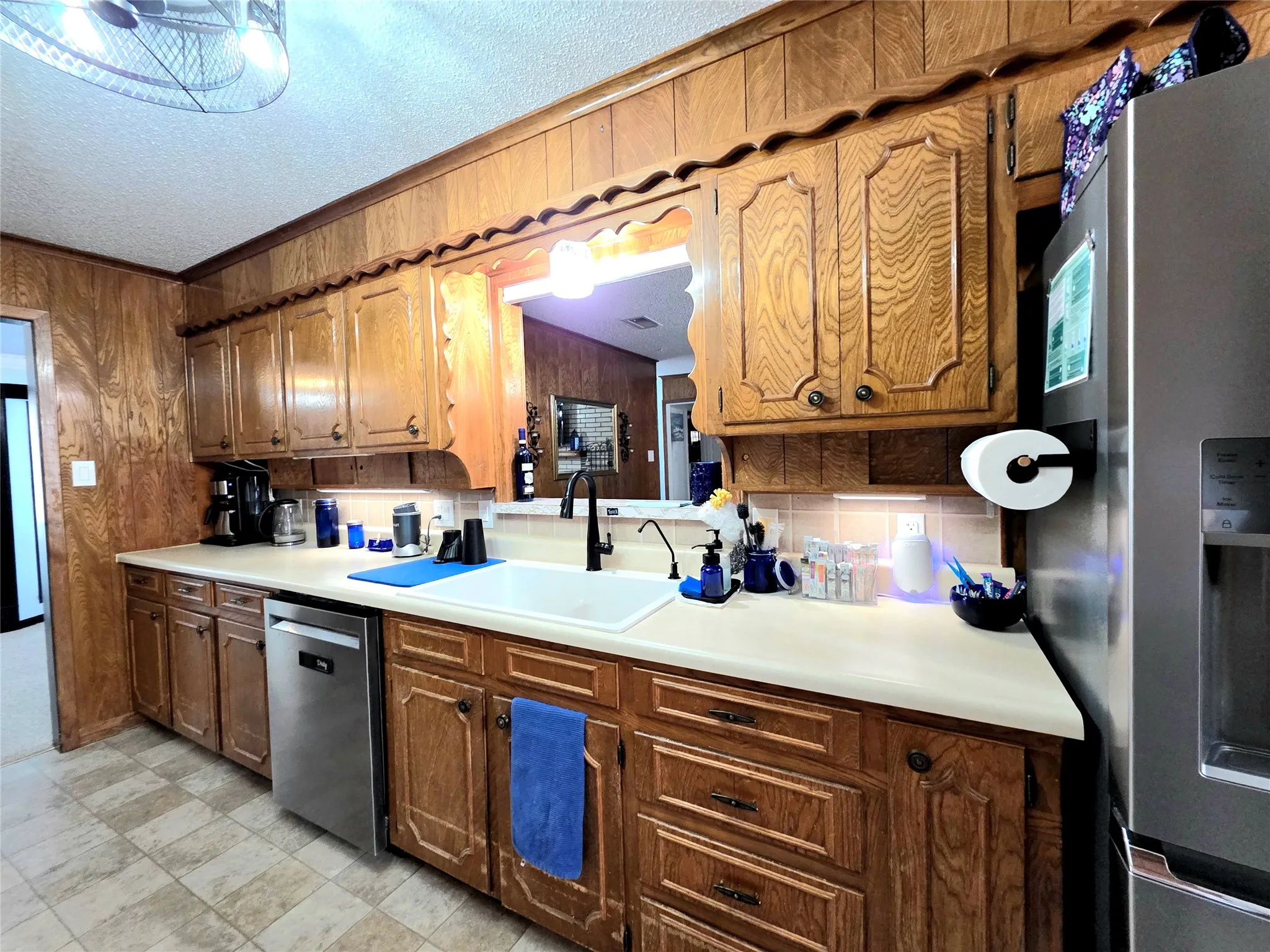 View two of the dishwasher, sink and refrigerator area with ample cabinet space including spice cabinets.