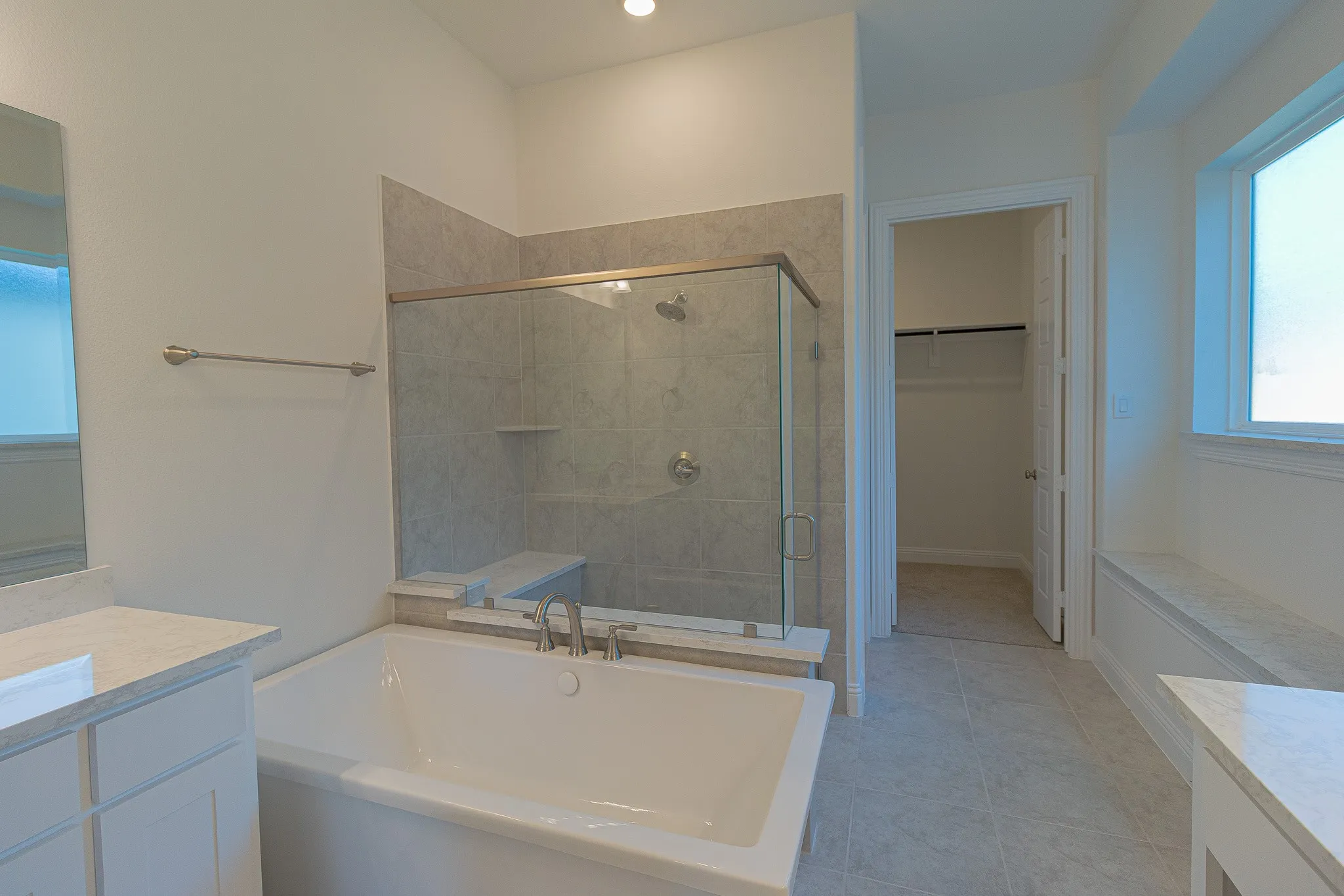 Full bath featuring vanity, a tub to relax in, a shower stall, and a spacious closet