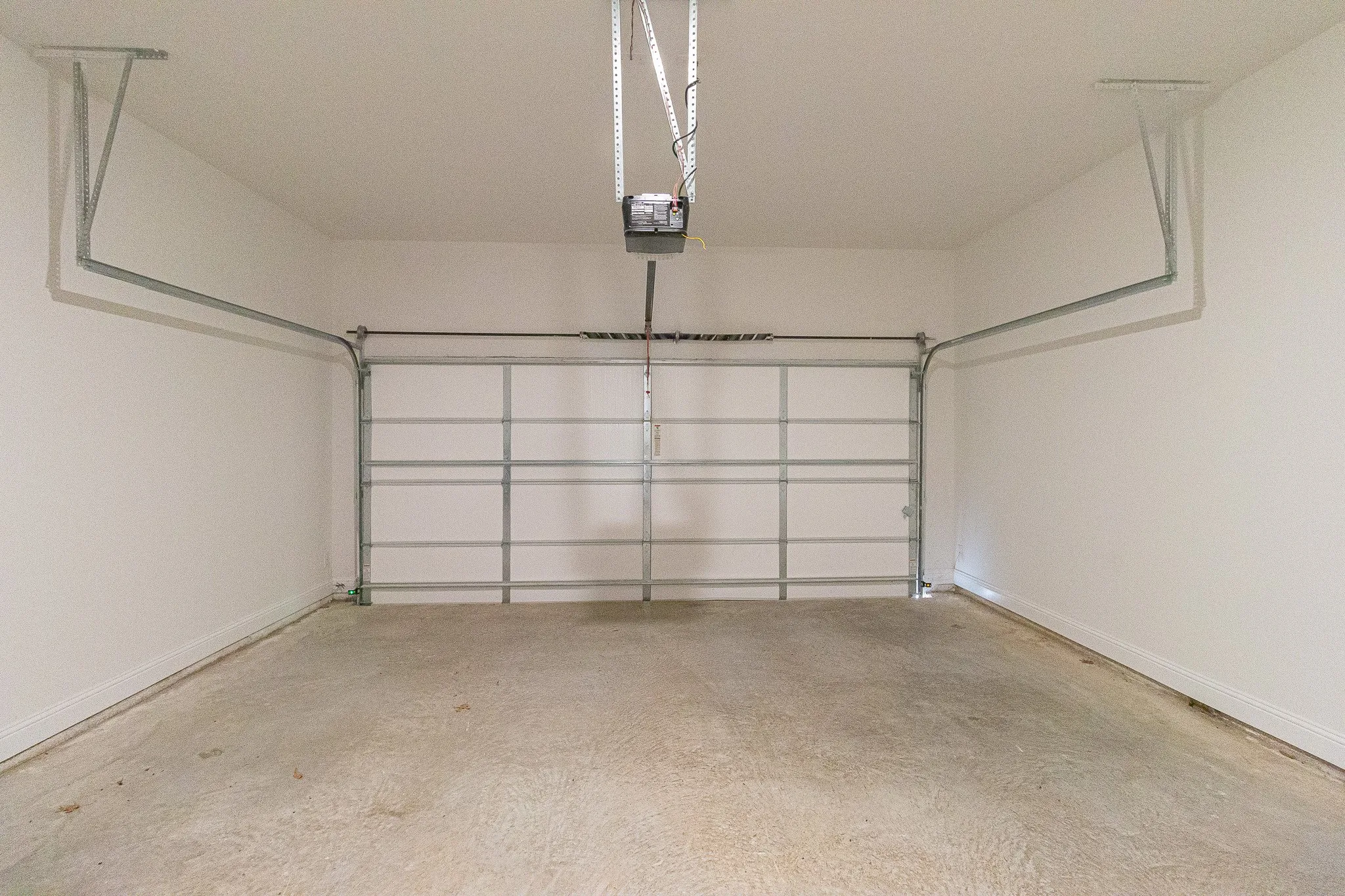 Garage featuring a garage door opener and baseboards