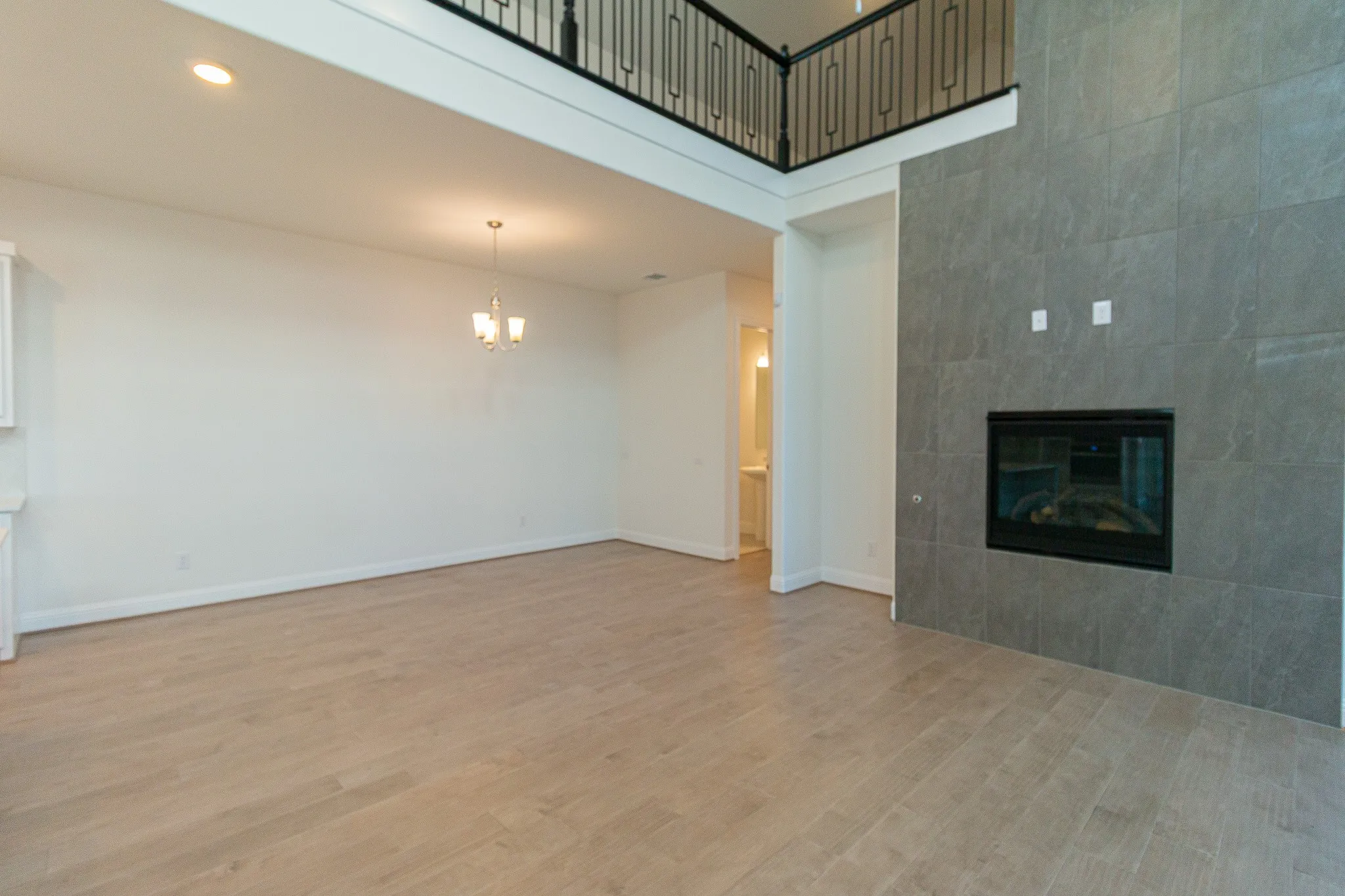 Unfurnished living room with a chandelier, a tiled fireplace, and light wood finished floors