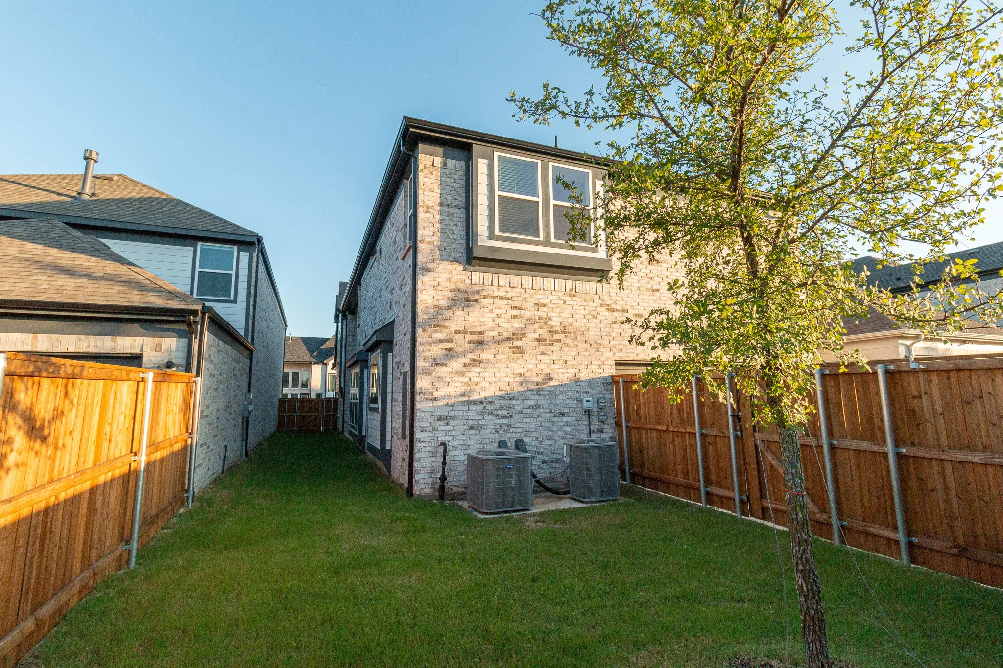Rear view of property featuring brick siding and a fenced backyard