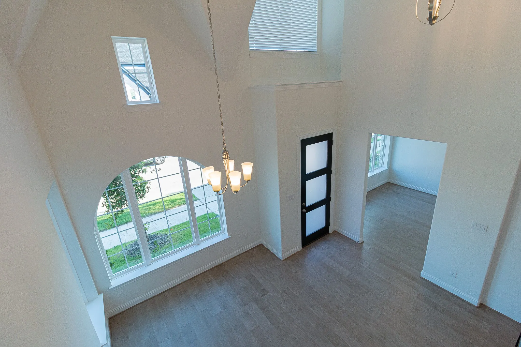 Entryway featuring a towering ceiling, a chandelier, healthy amount of natural light, and wood finished floors