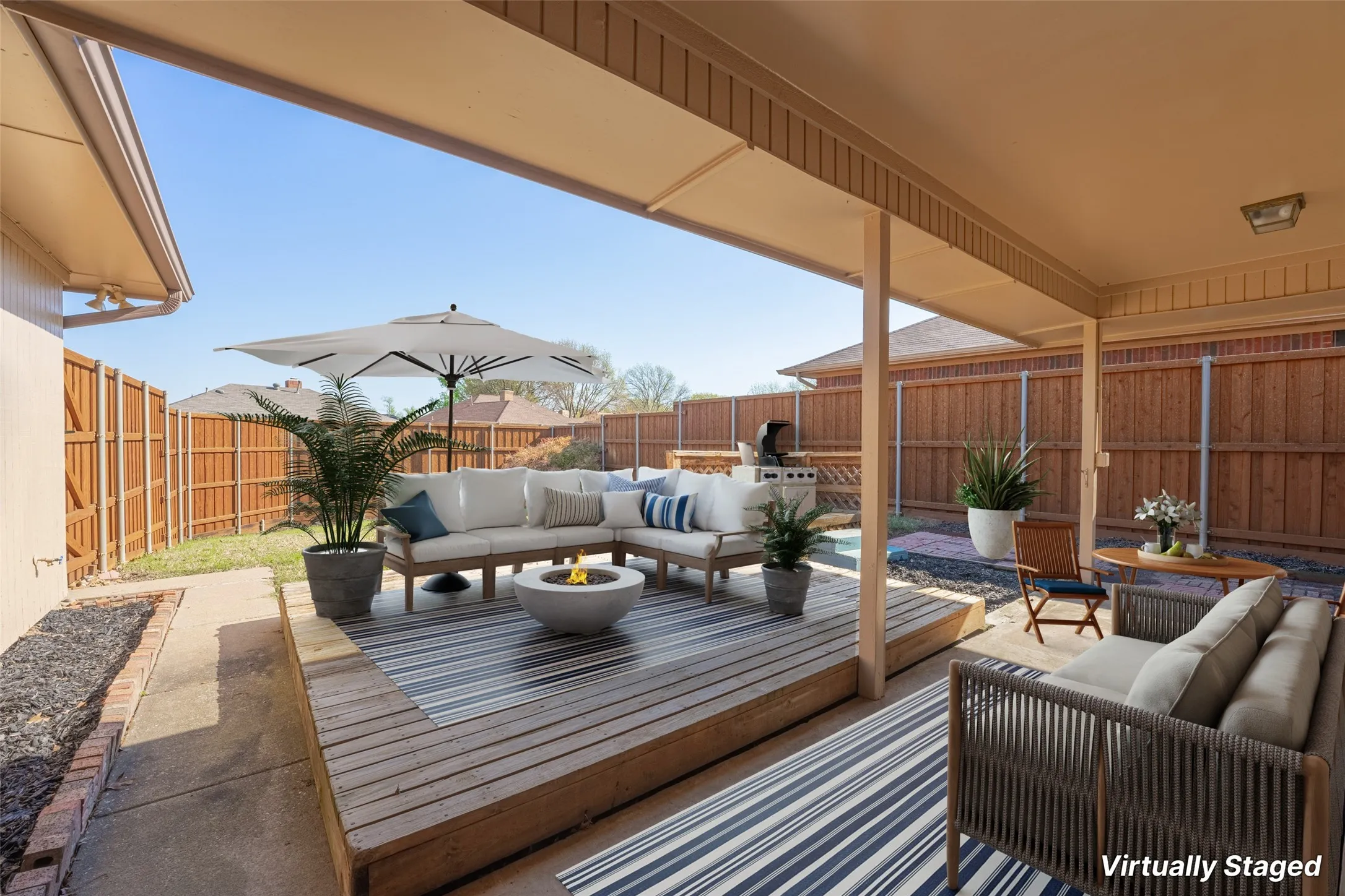 Expansive backyard featuring a covered patio, wood deck, and perimeter fencing