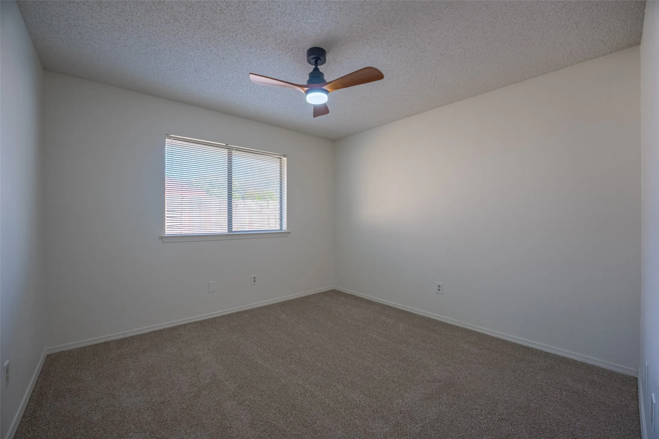 Neutral wall color, window with blinds, ceiling fan with integrated lighting, and carpet flooring