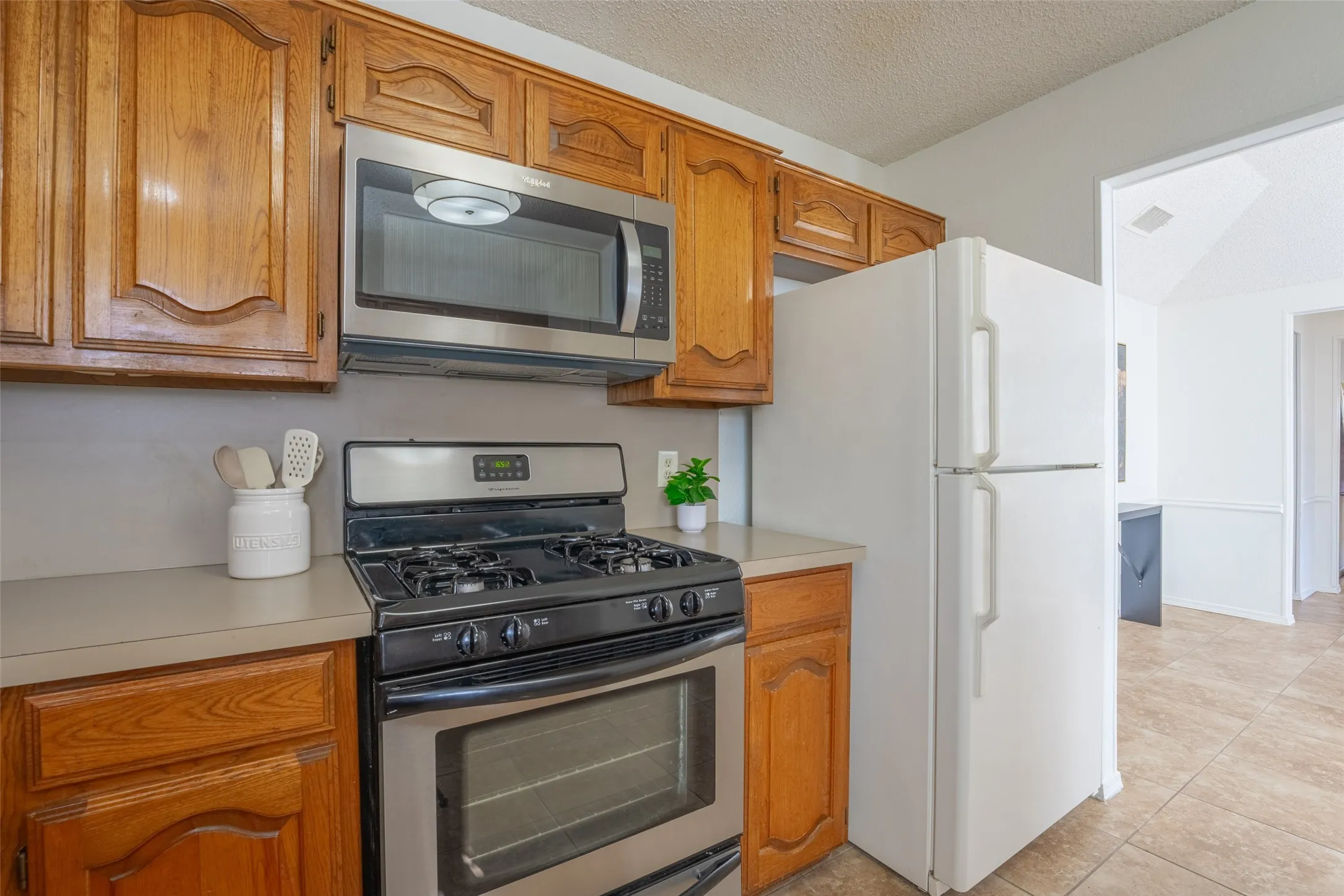 Kitchen with wood cabinetry, stainless steel microwave, and a gas range