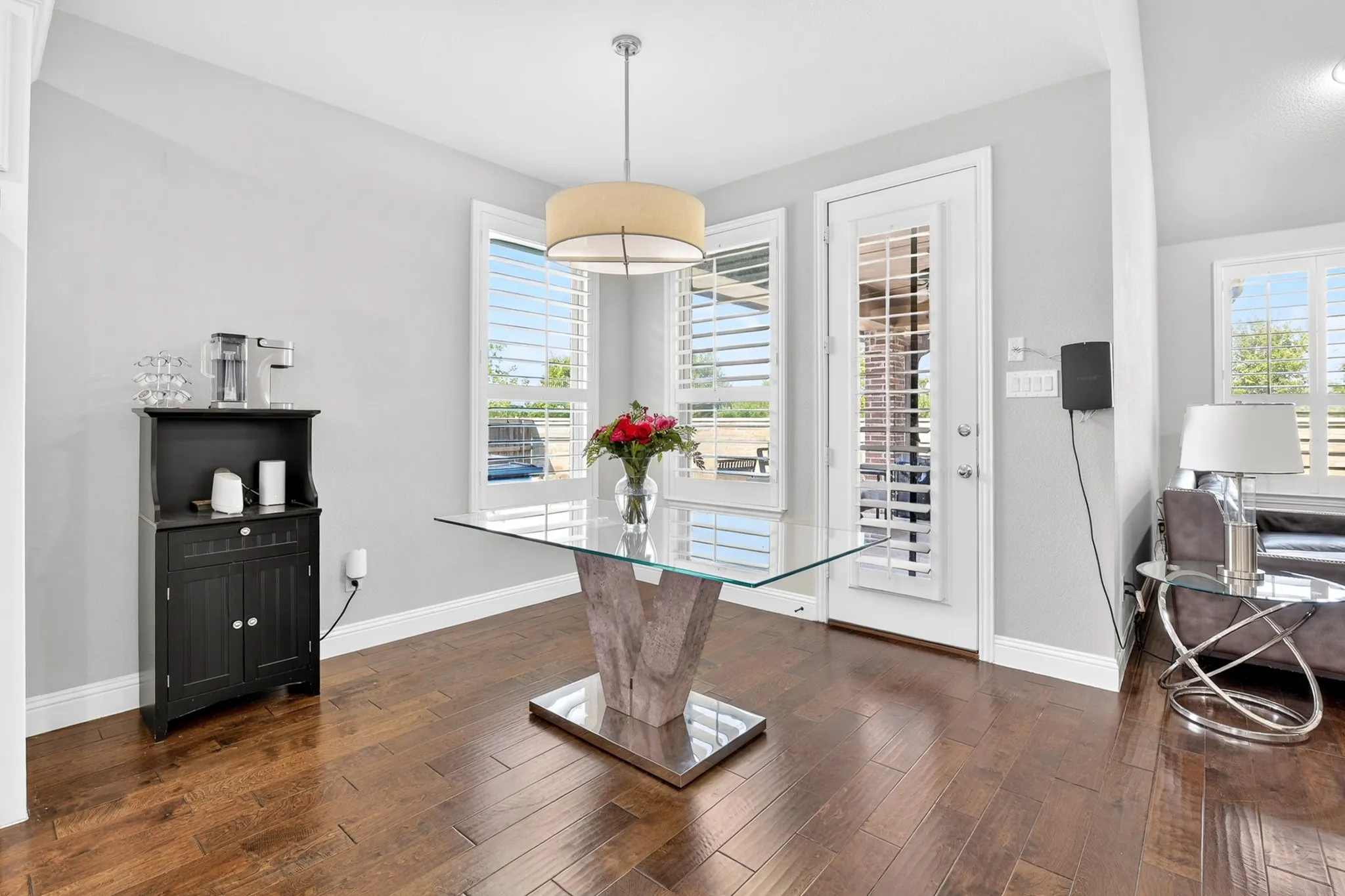 Hardwood-finish flooring, white plantation shutters, pendant lighting, and a glass-paneled exterior door