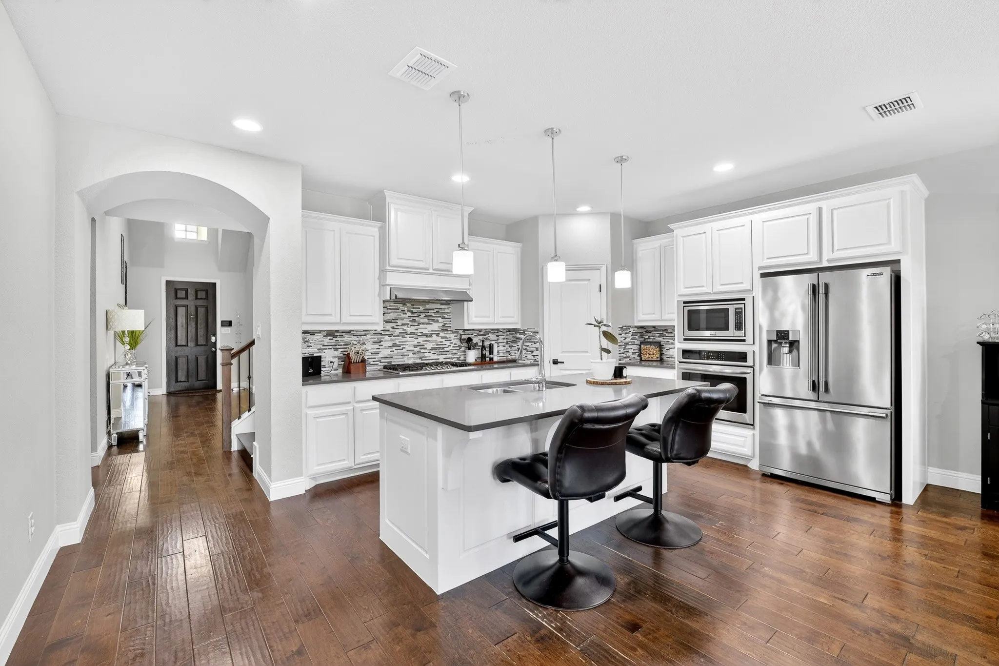 Kitchen featuring white cabinetry, a large center island with seating, stainless steel appliances, and wood-finish flooring