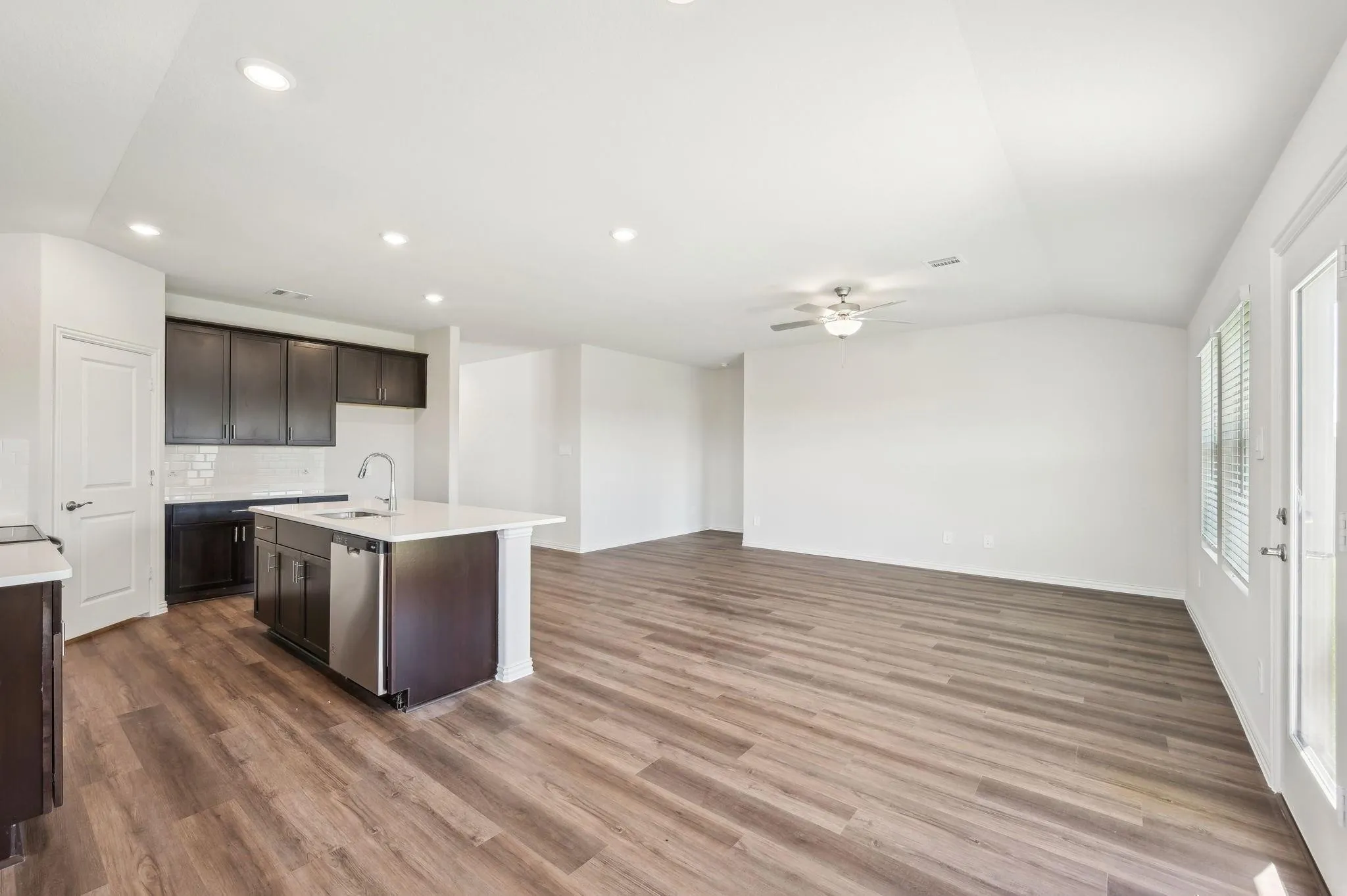 Kitchen with ceiling fan, vaulted ceiling, dark brown cabinets, a sink, and light countertops