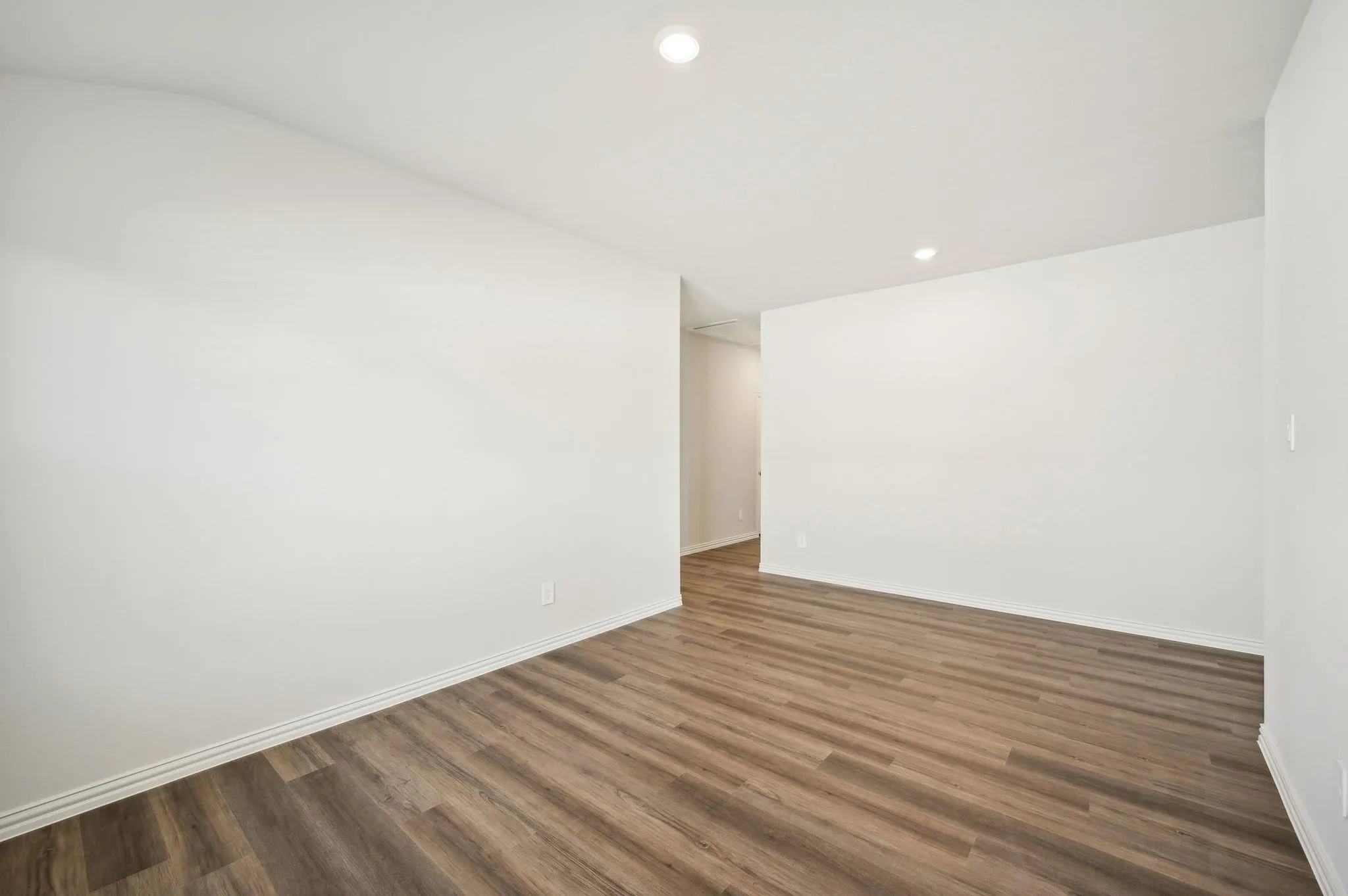 Spare room featuring recessed lighting, baseboards, wood finished floors, and lofted ceiling
