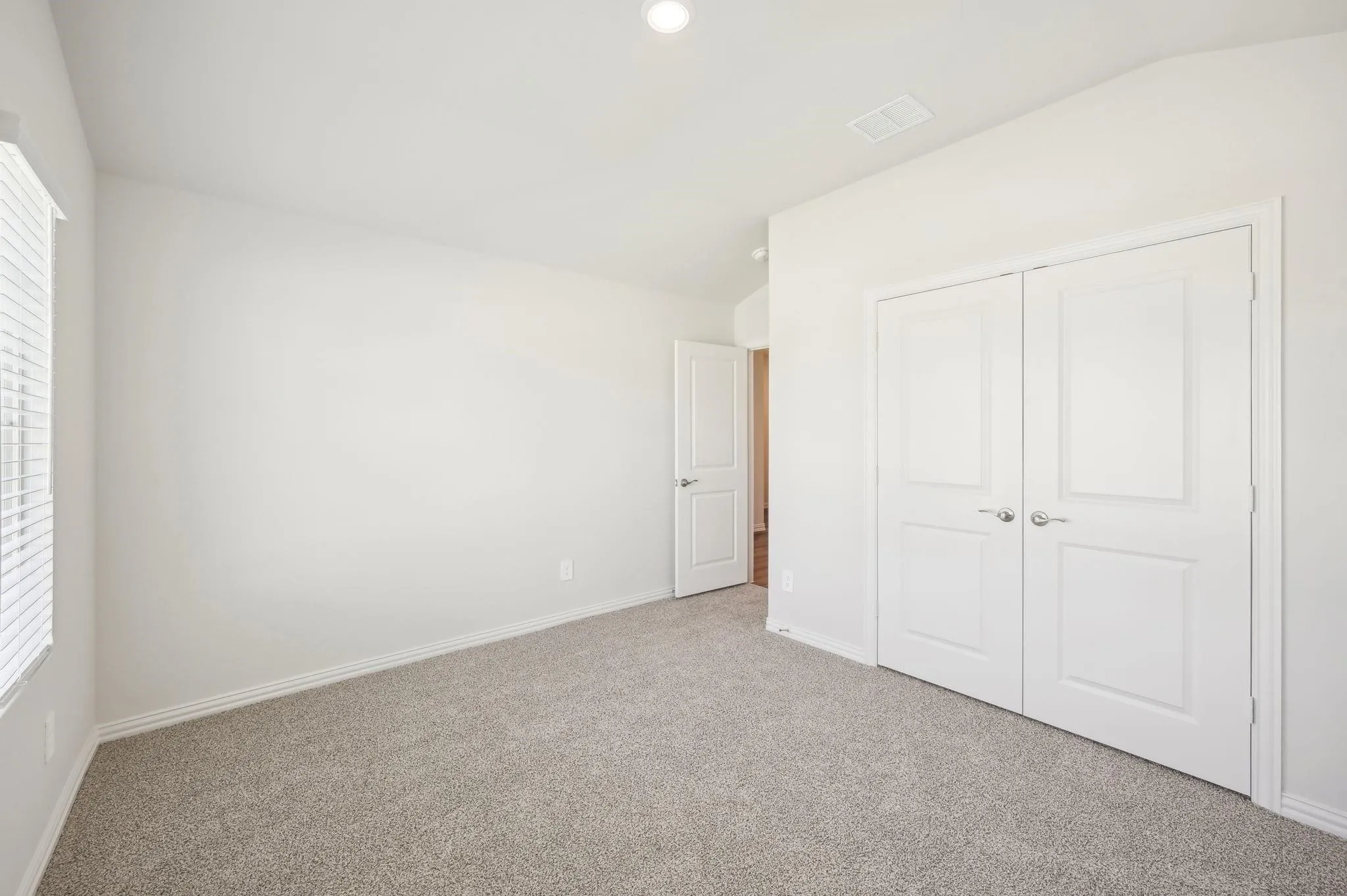 Unfurnished bedroom featuring carpet floors, multiple windows, and lofted ceiling