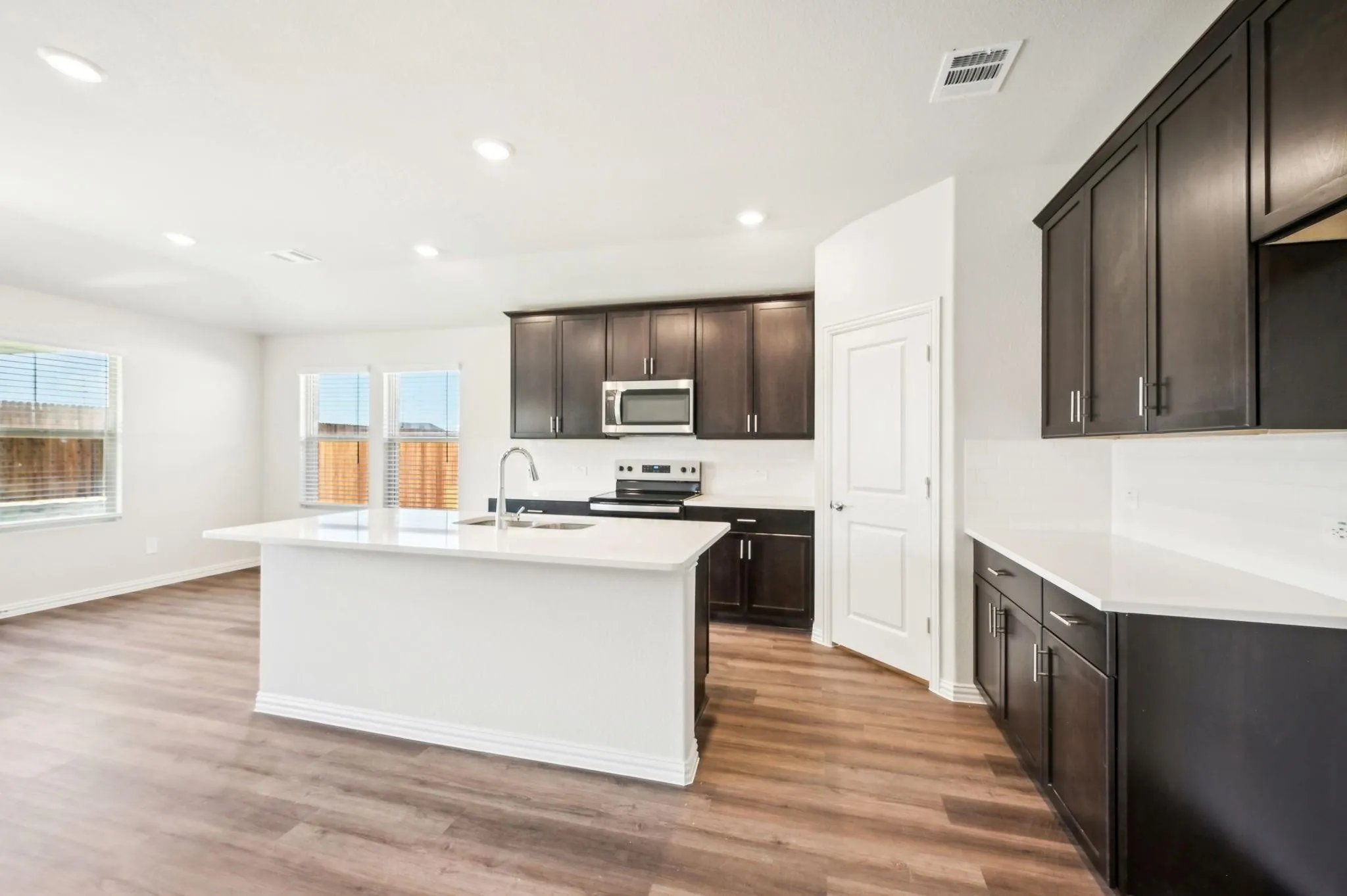 Kitchen with stainless steel appliances, visible vents, a sink, and light wood finished floors