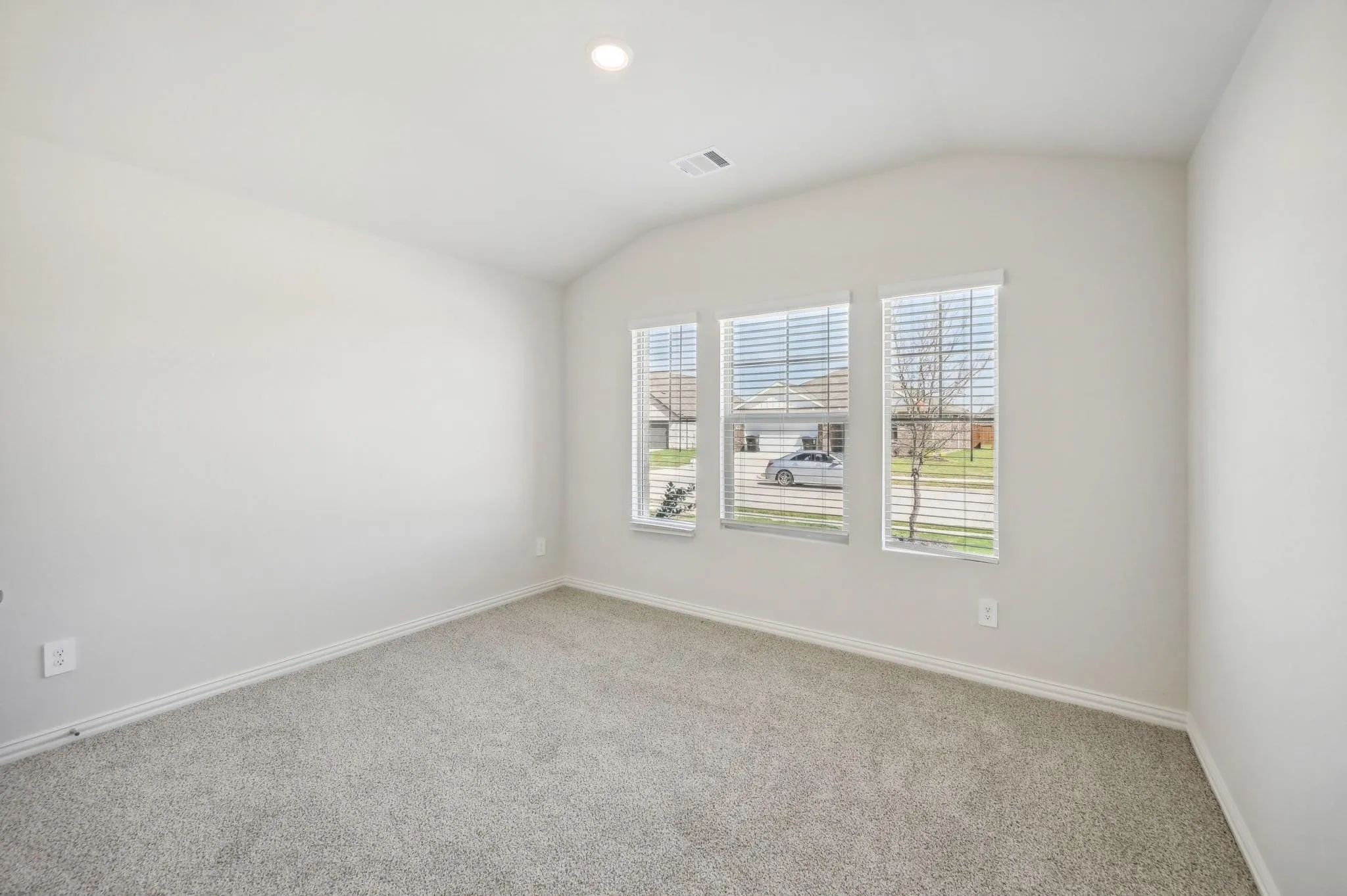 Spare room featuring visible vents, baseboards, carpet, and lofted ceiling