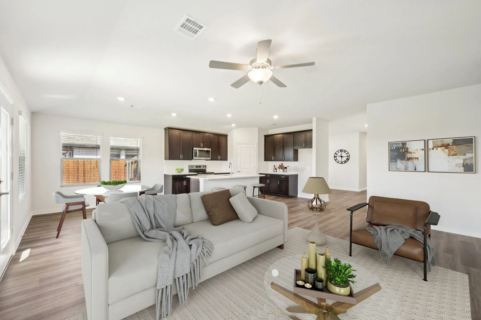 Living room featuring light wood-style floors, baseboards, a ceiling fan, and visible vents
