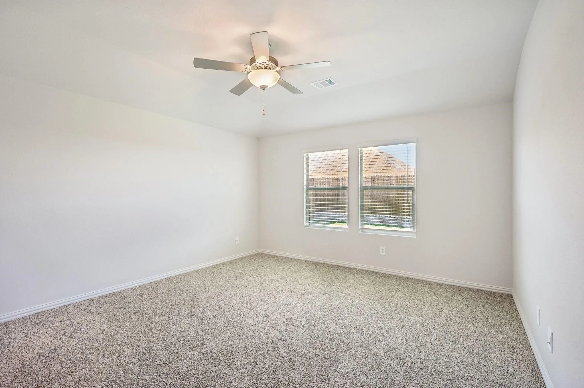 Empty room featuring carpet floors, baseboards, a ceiling fan, and visible vents