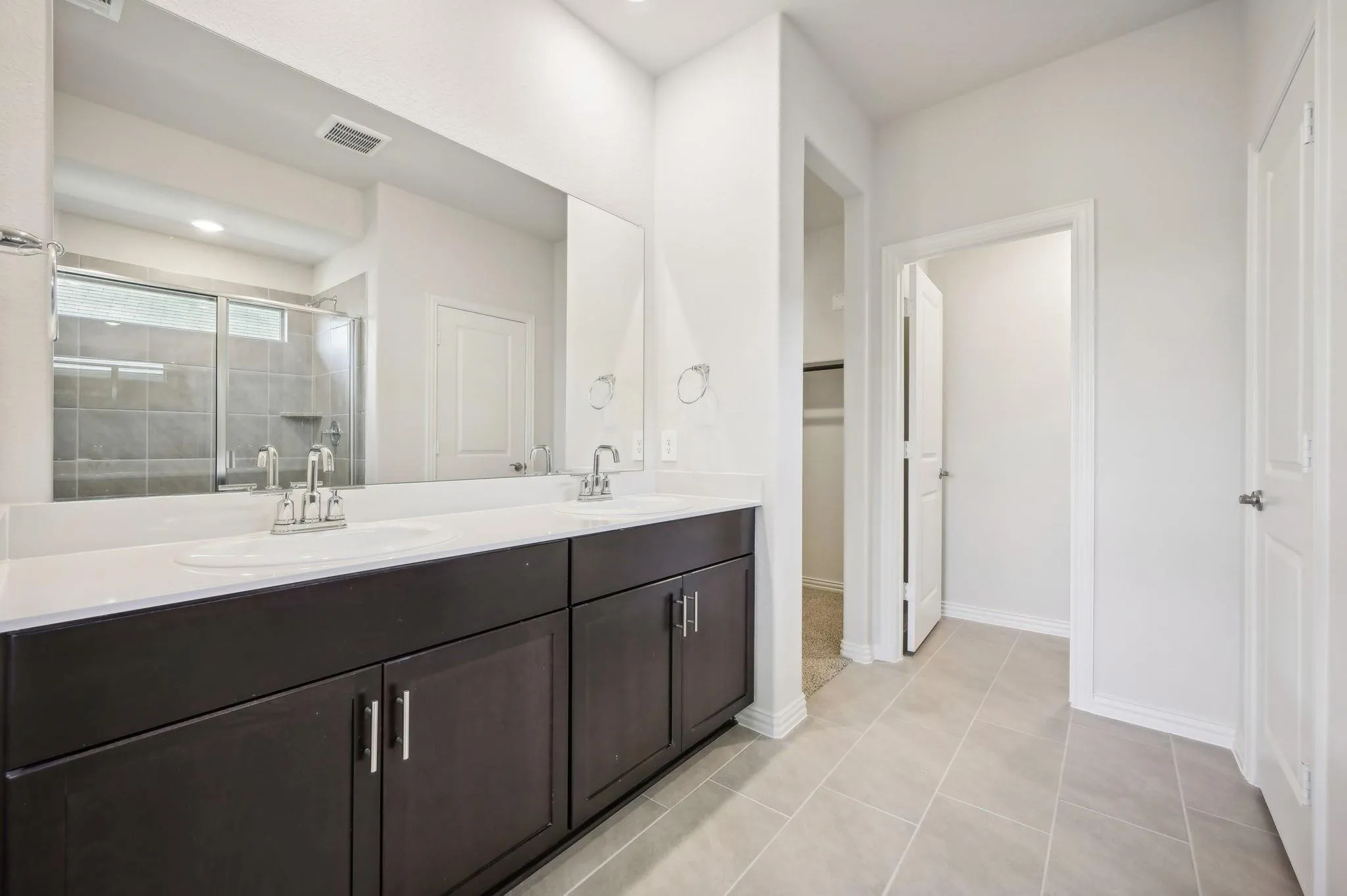 Bathroom with visible vents, a sink, double vanity, and a shower stall