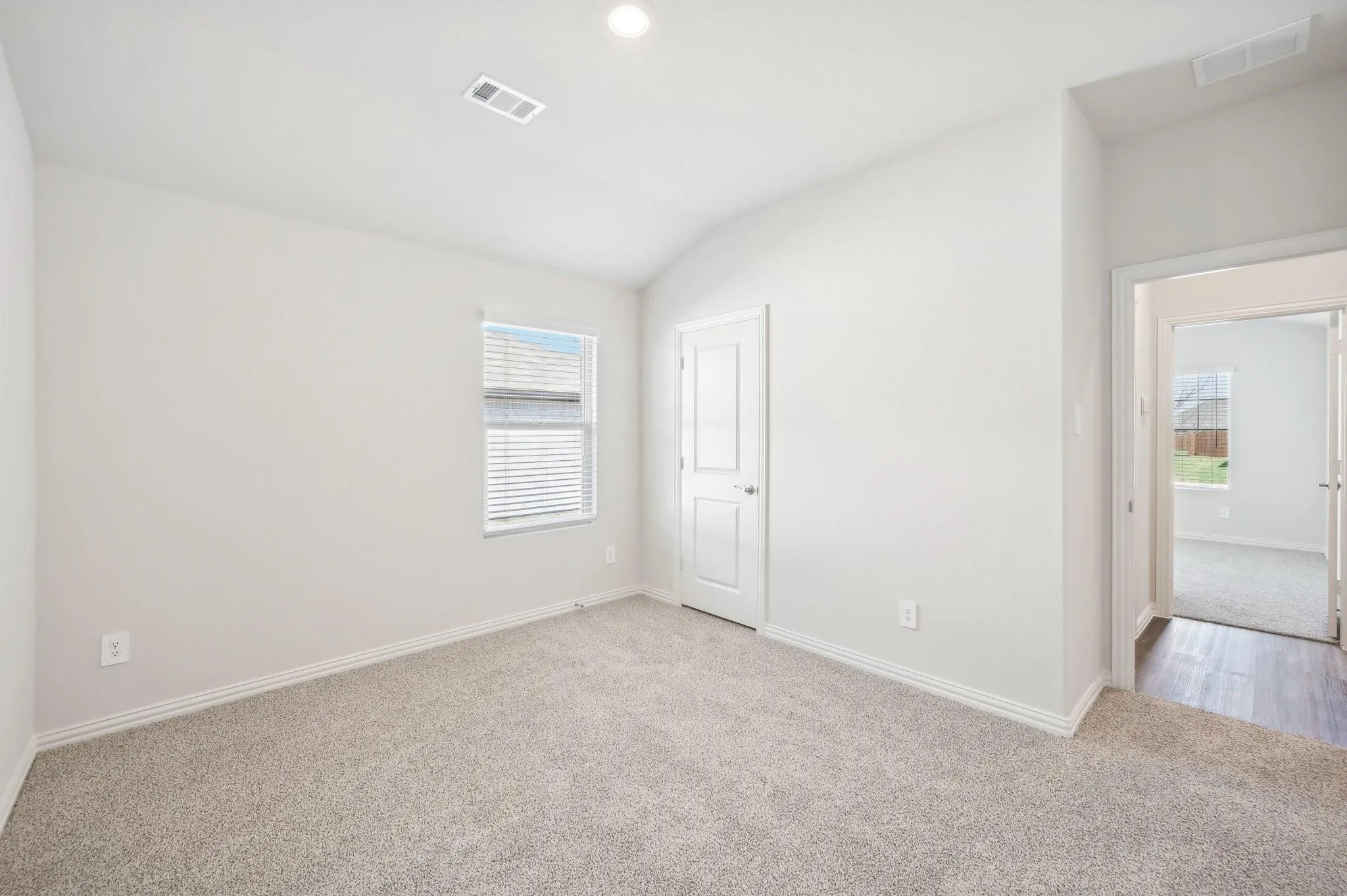 Empty room with a wealth of natural light, light carpet, and visible vents