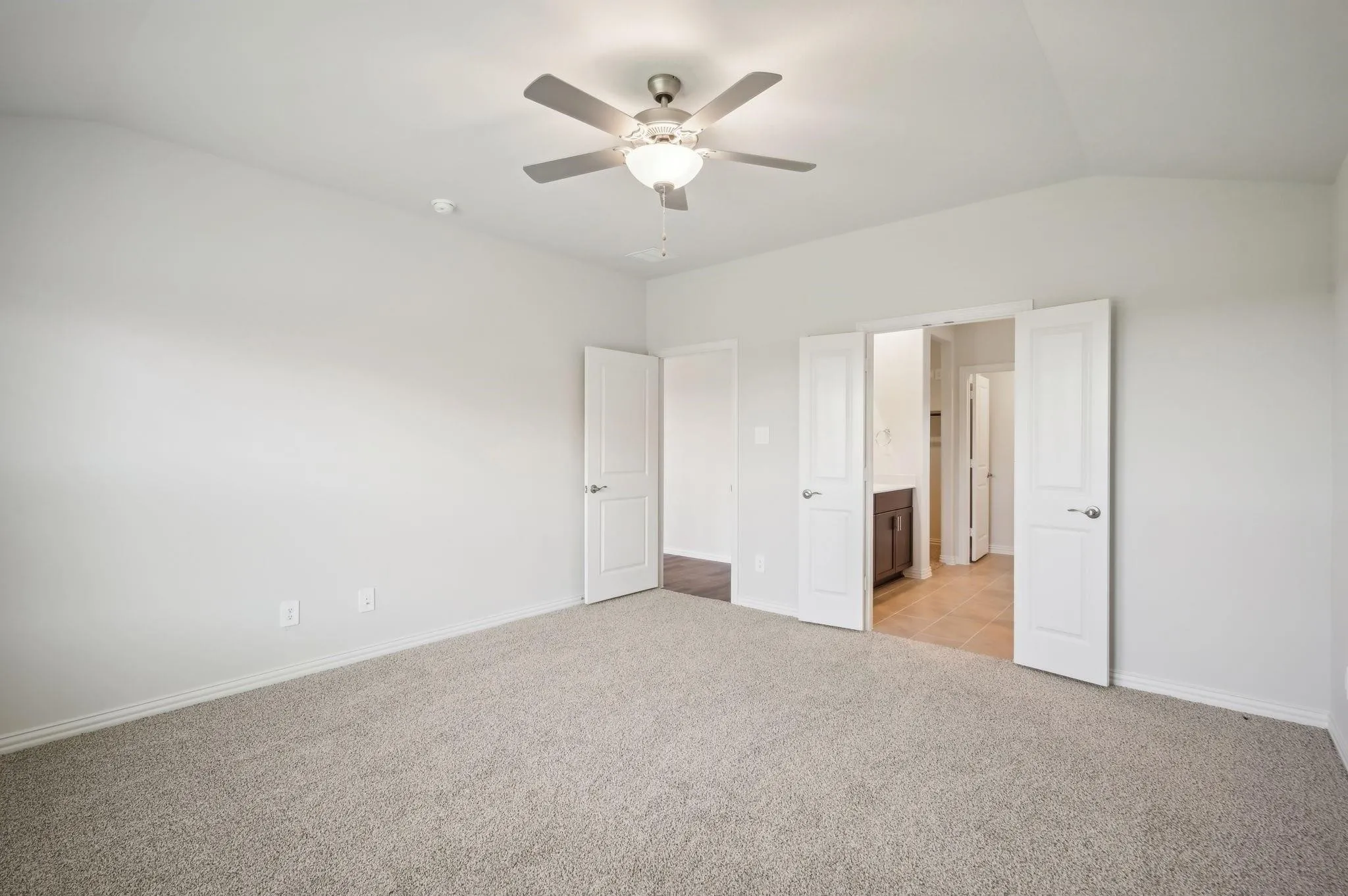Unfurnished bedroom with baseboards, light colored carpet, ceiling fan, and vaulted ceiling
