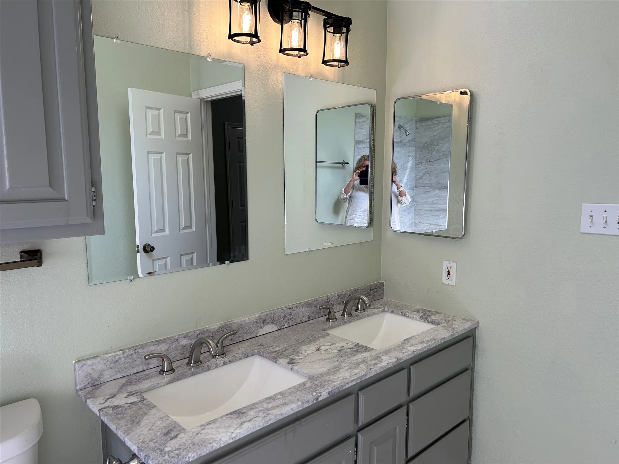 Updated light fixture in the primary bathroom, dual sinks and plenty of storage.
