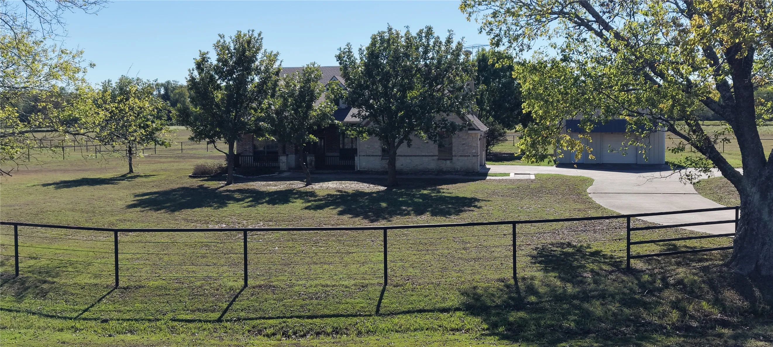 Single-story brick residence with an attached garage, featuring a paved driveway and a separate outbuilding