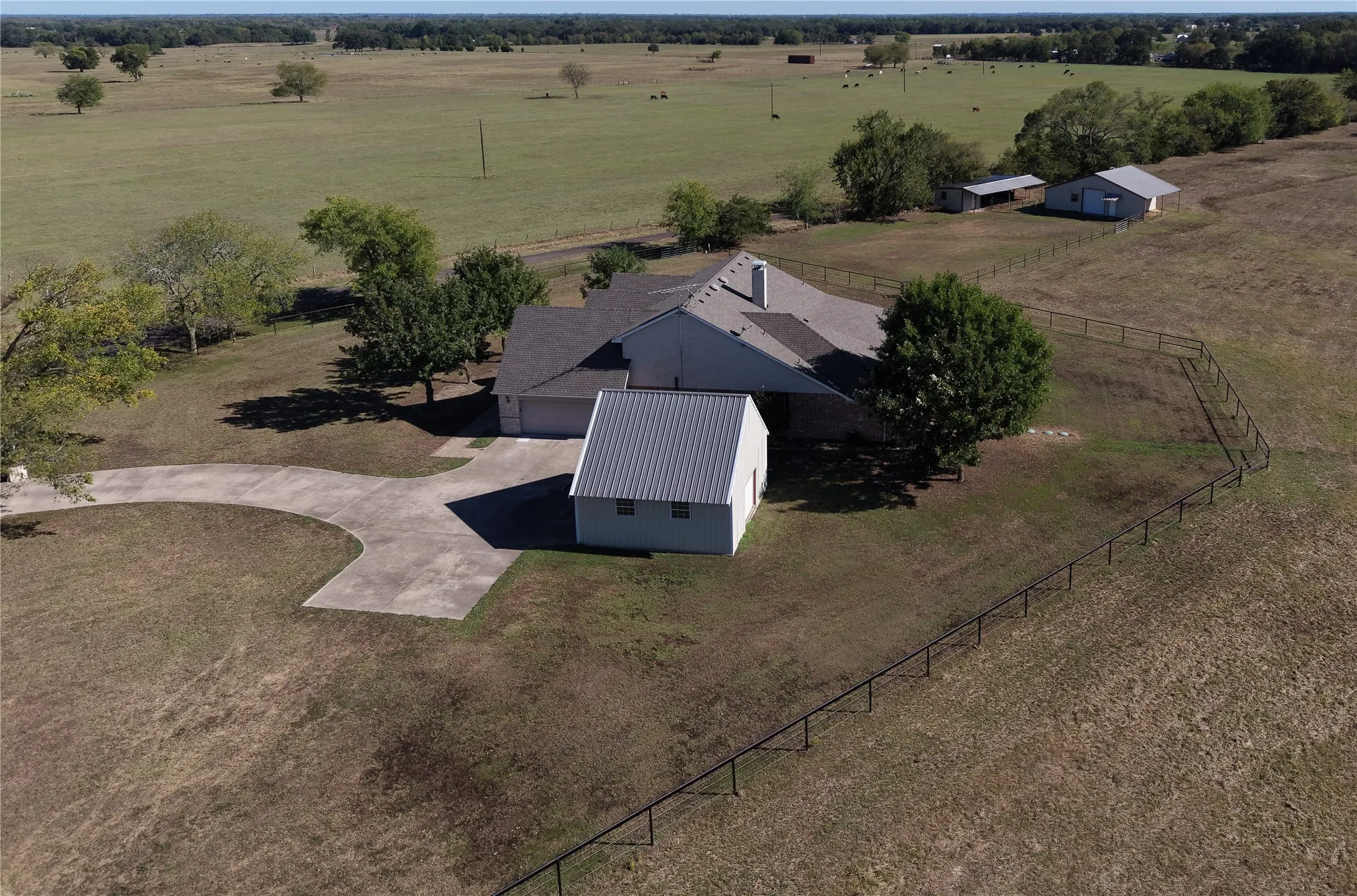 Expansive property featuring a residence with an attached garage, a separate outbuilding, and additional structures