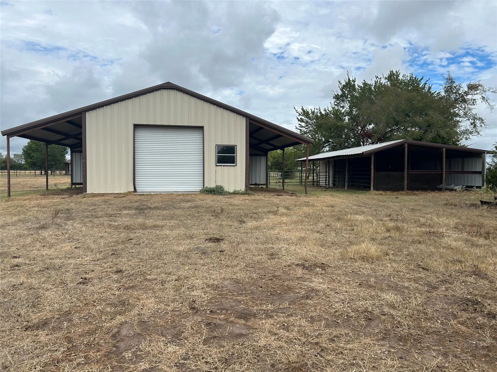Metal building with an overhead door, single window, and covered side extension