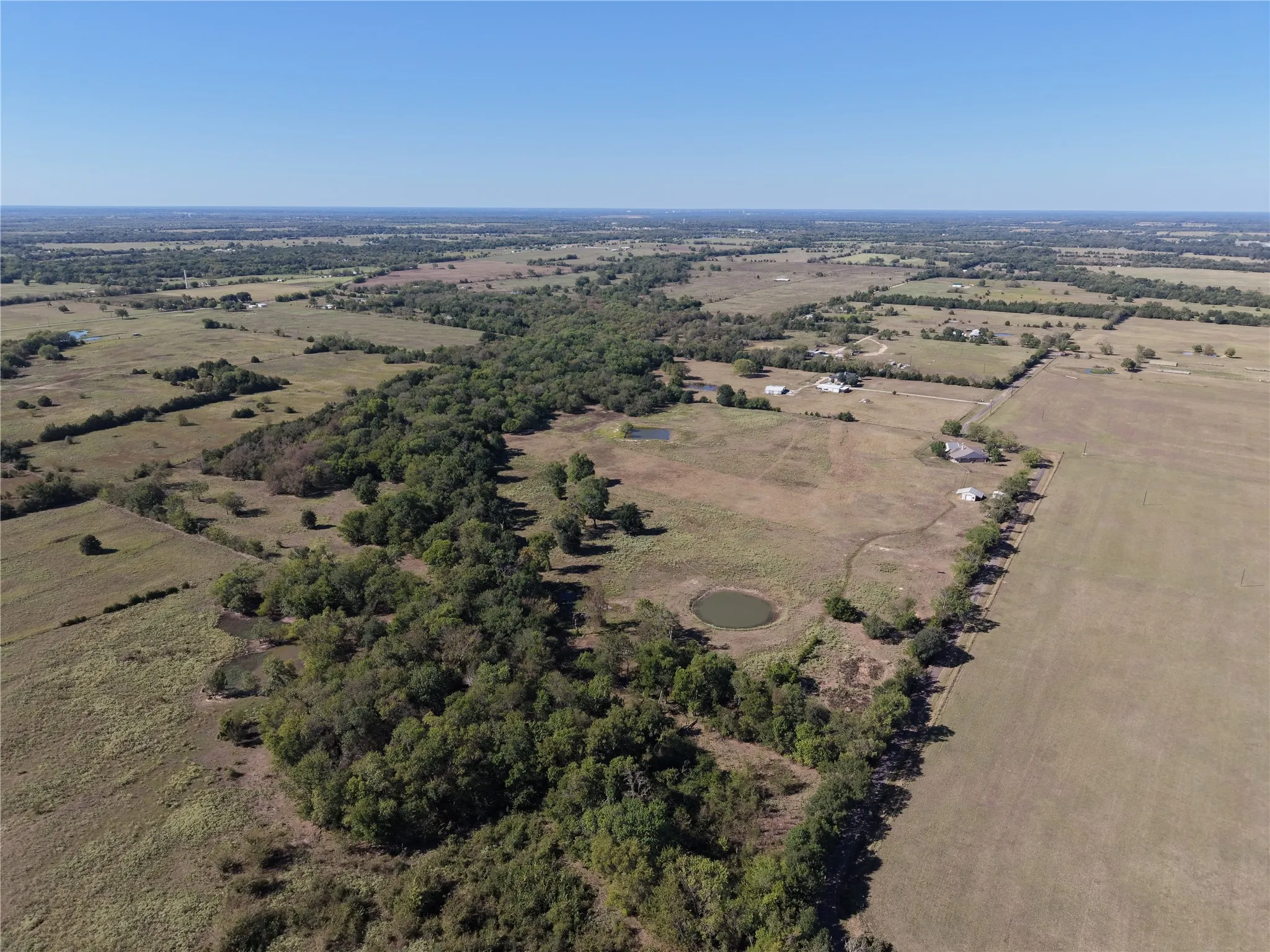 Expansive rural landscape featuring two visible ponds, mature tree lines, and scattered residential structures