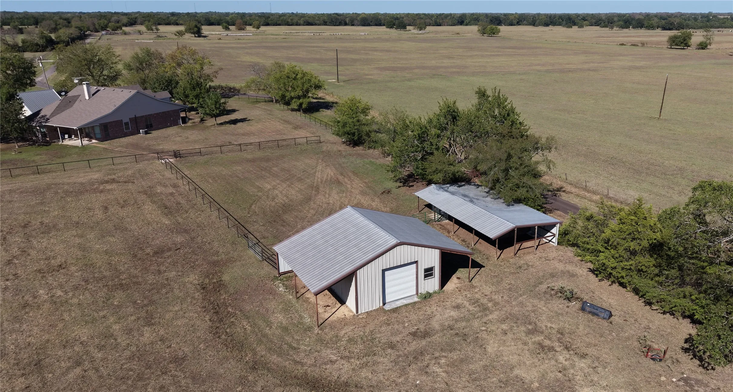 Expansive rural property featuring a main residence, fenced perimeter, detached shed, and an additional covered structure
