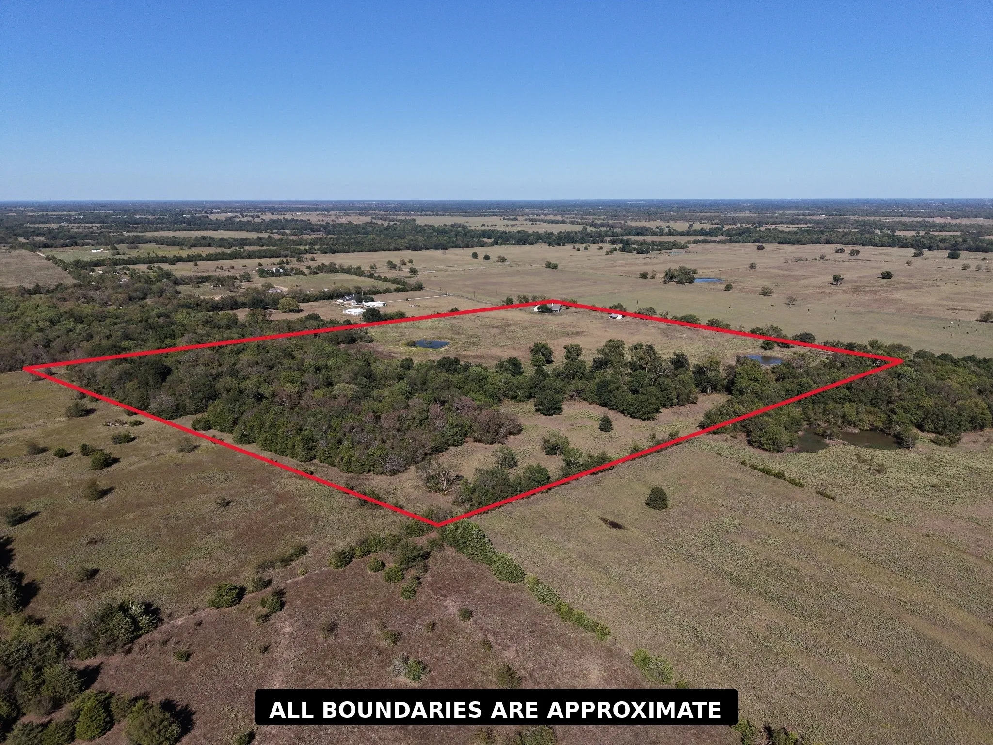 Expansive land parcel with open fields, wooded areas, and multiple ponds