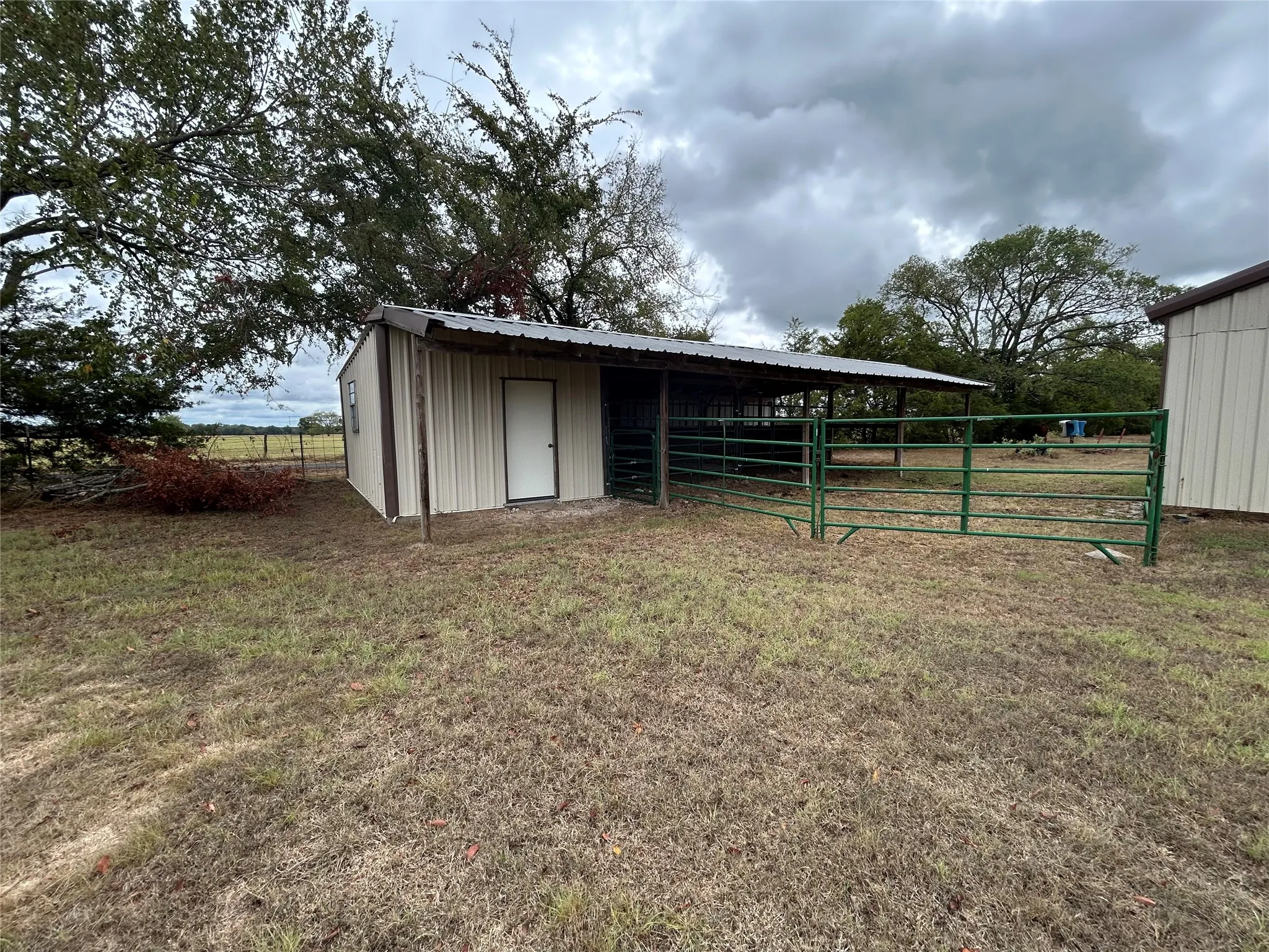 Corrugated metal outbuilding with an attached lean-to, metal roofing, and a privacy door