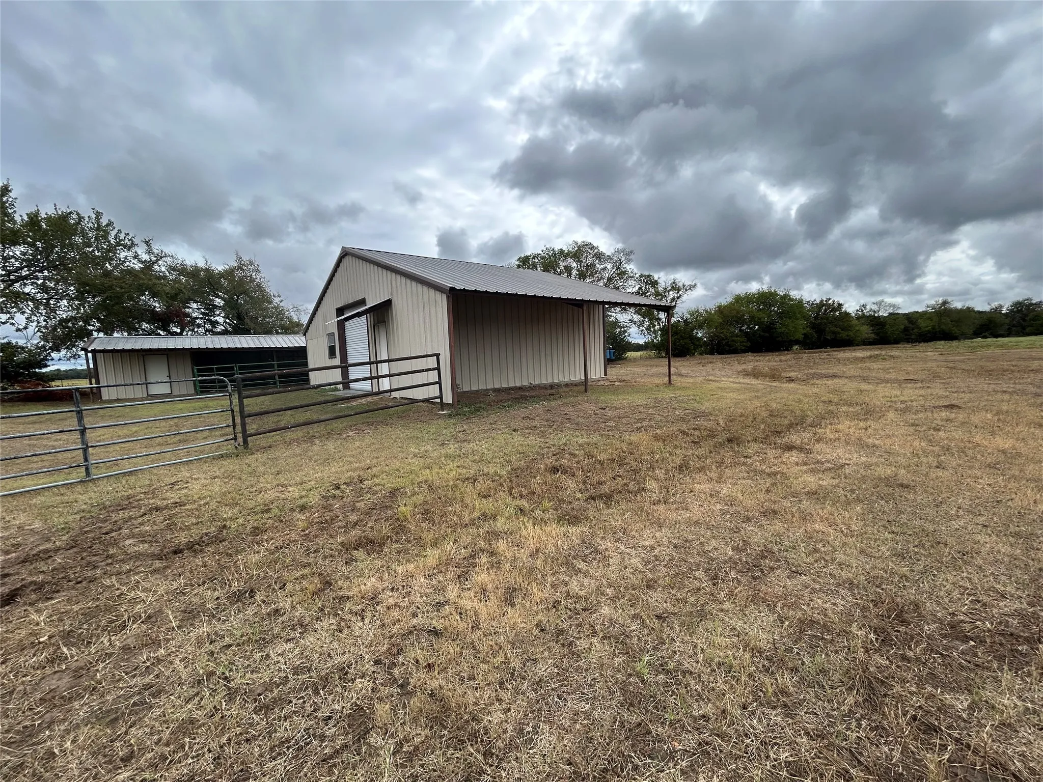 Metal-sided outbuilding with a covered entry and metal roofing, accompanied by a second metal-sided structure