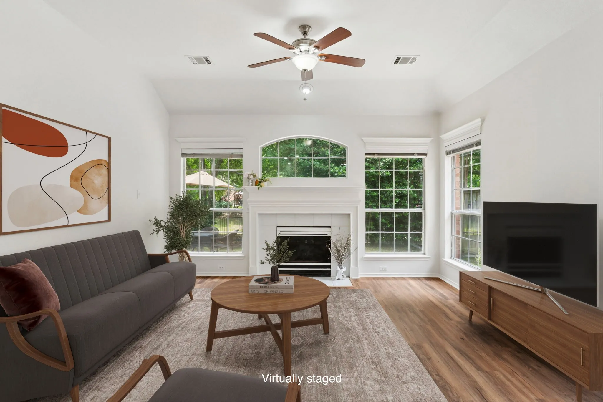 Vaulted ceiling with a ceiling fan, fireplace with a mantel, wood-finish flooring, and multiple windows