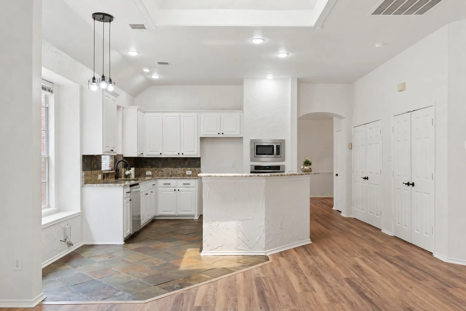 Kitchen featuring white cabinetry, stainless steel appliances, granite countertops, and stone tile flooring