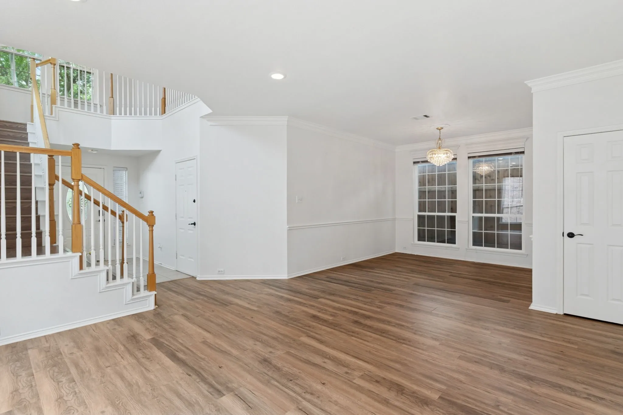Wood-finish flooring throughout, with a grand staircase featuring white spindles and wood handrails
