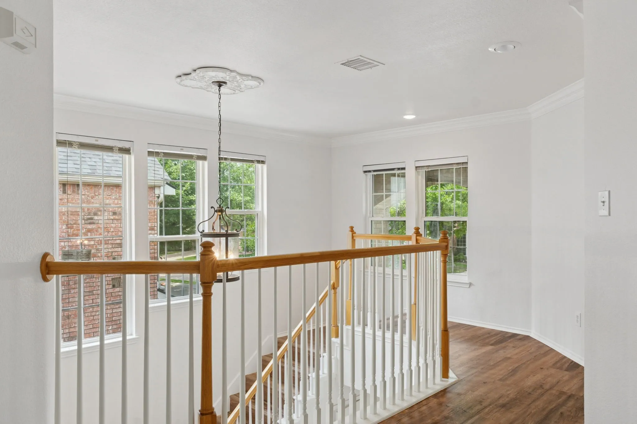 Staircase with wood-finish handrails, white balusters, and recessed lighting