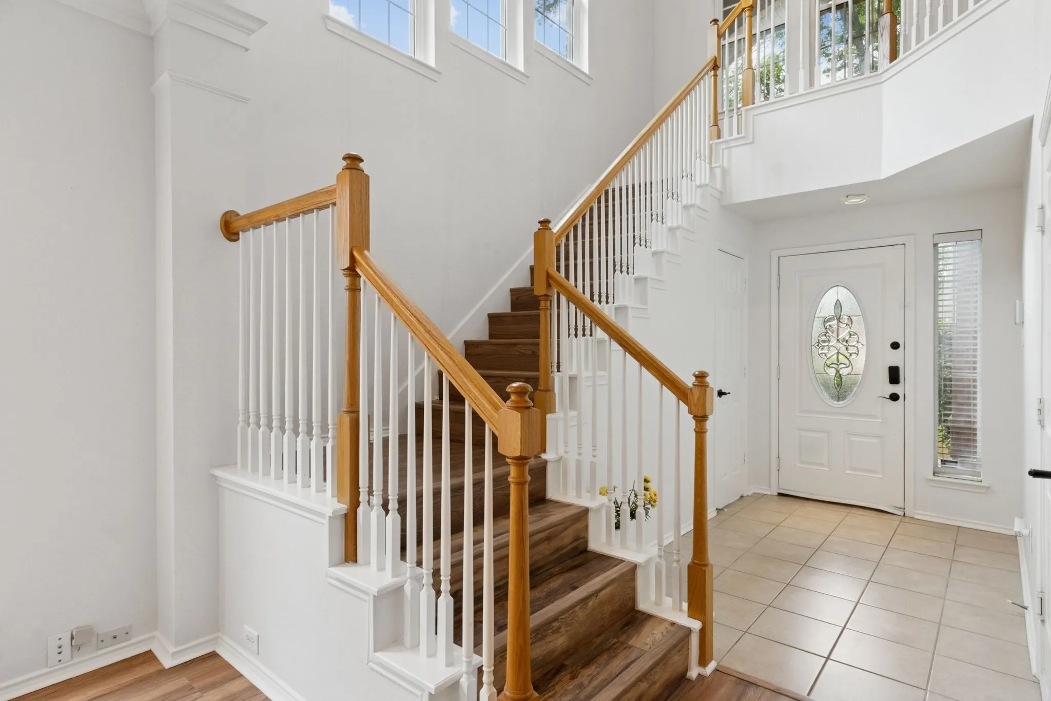 Two-story entryway featuring a wood-finish staircase with white risers and balusters