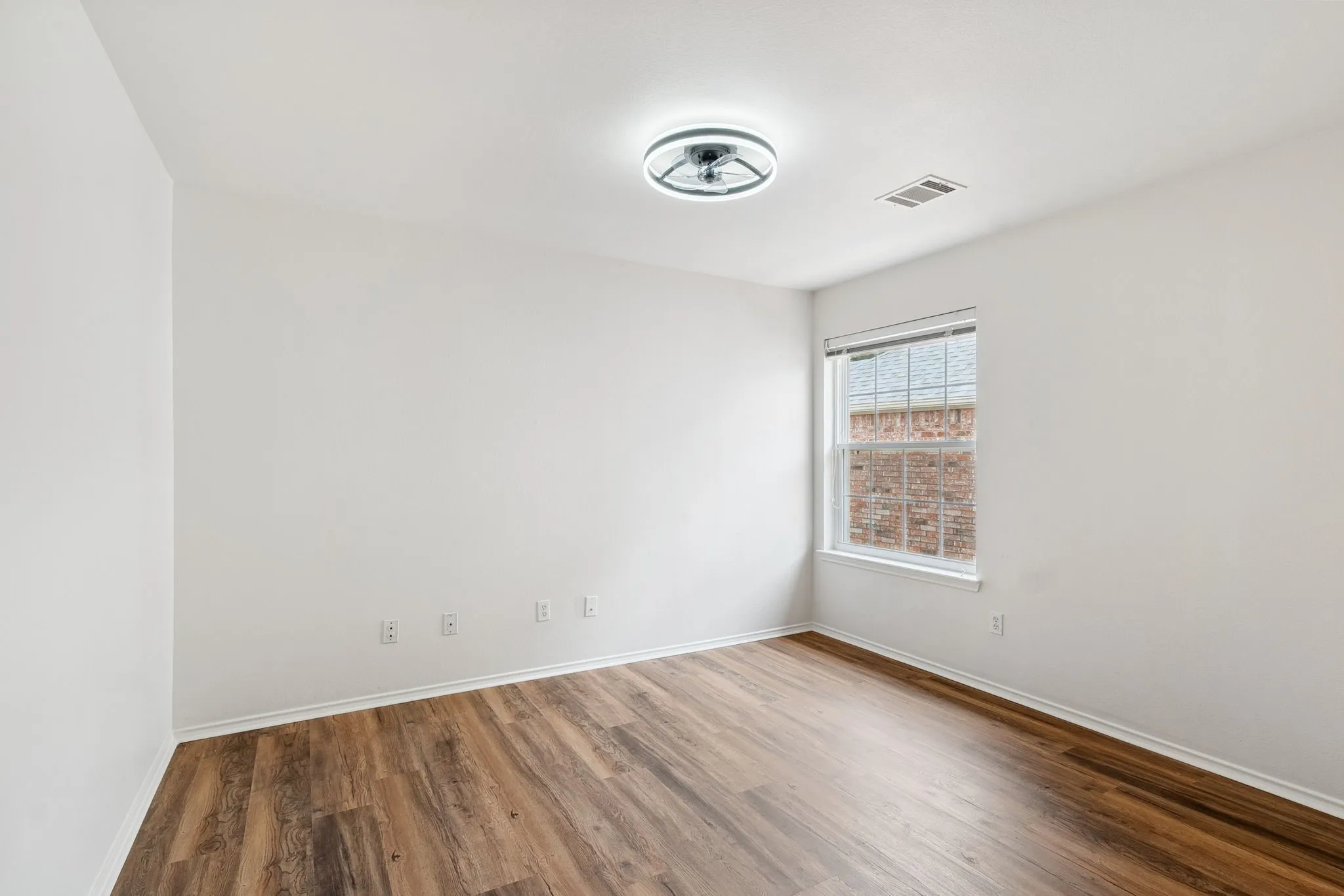 Wood-finish flooring with white baseboards, single window, and flush mount lighting