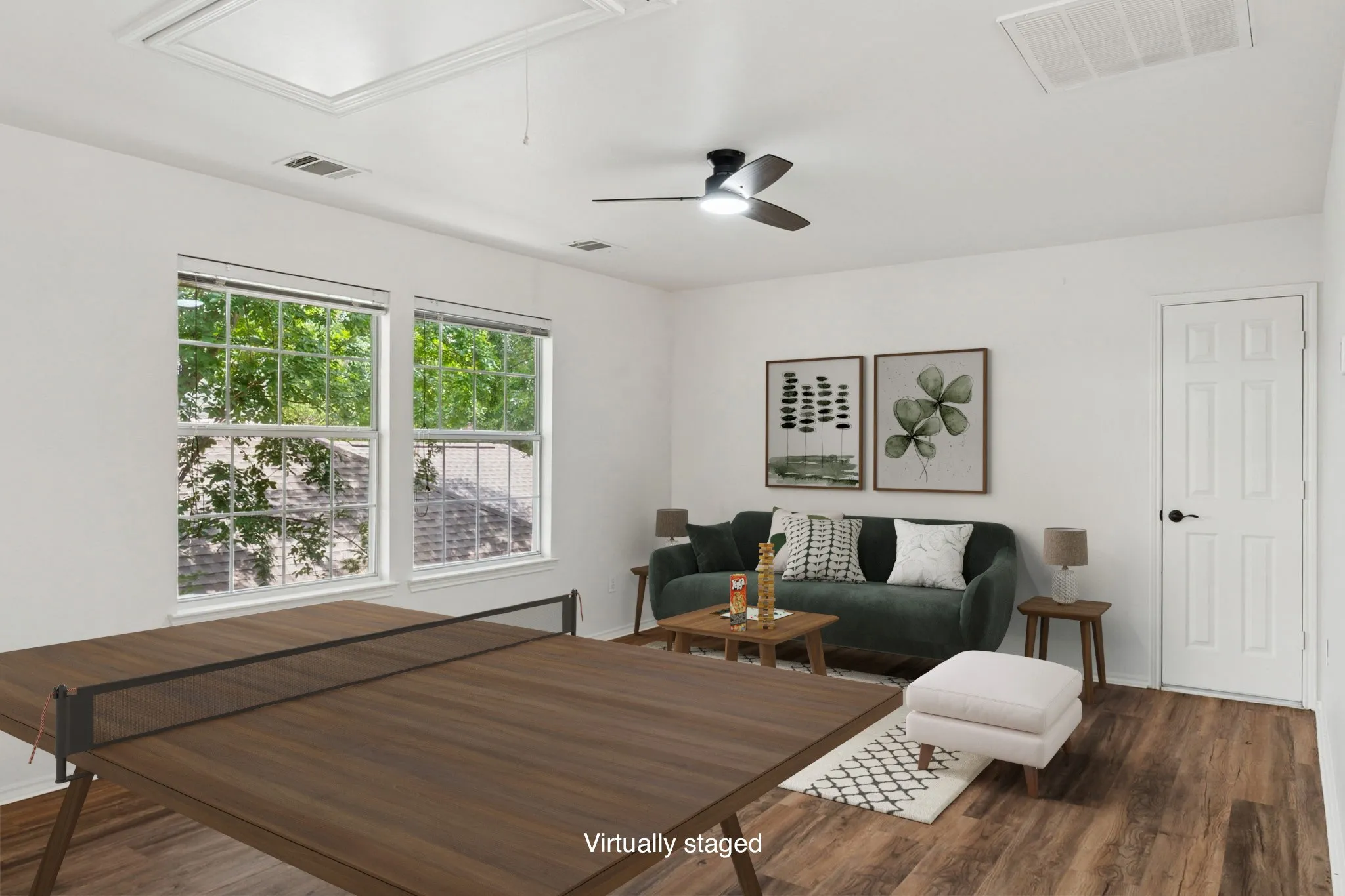 Dual windows, wood-finish flooring, ceiling fan, white paneled door, and a clean white color palette