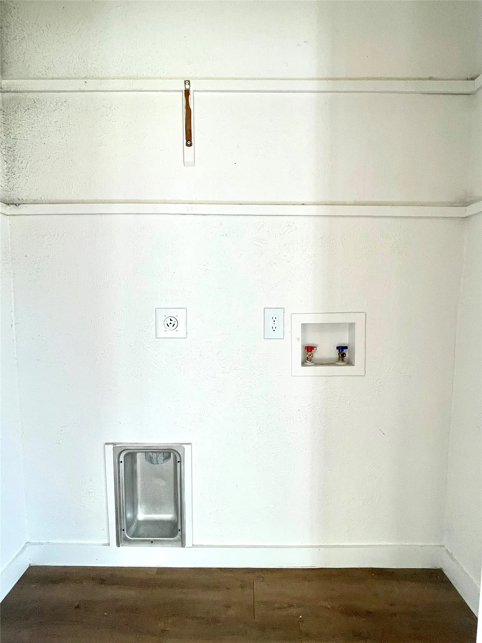 Clothes washing area with dark hardwood / wood-style flooring and hookup for a washing machine