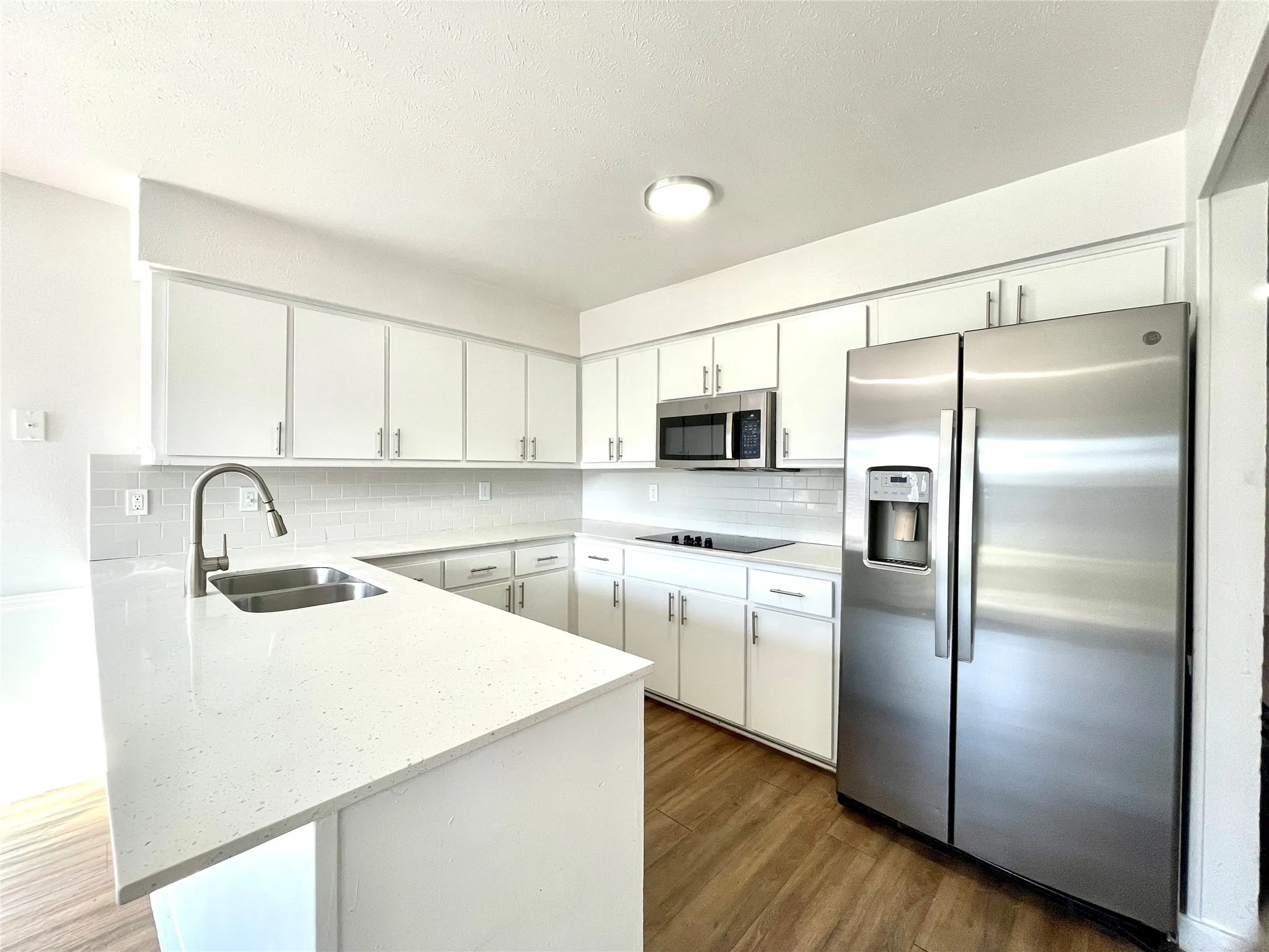 Kitchen with sink, stainless steel appliances, tasteful backsplash, and white cabinetry
