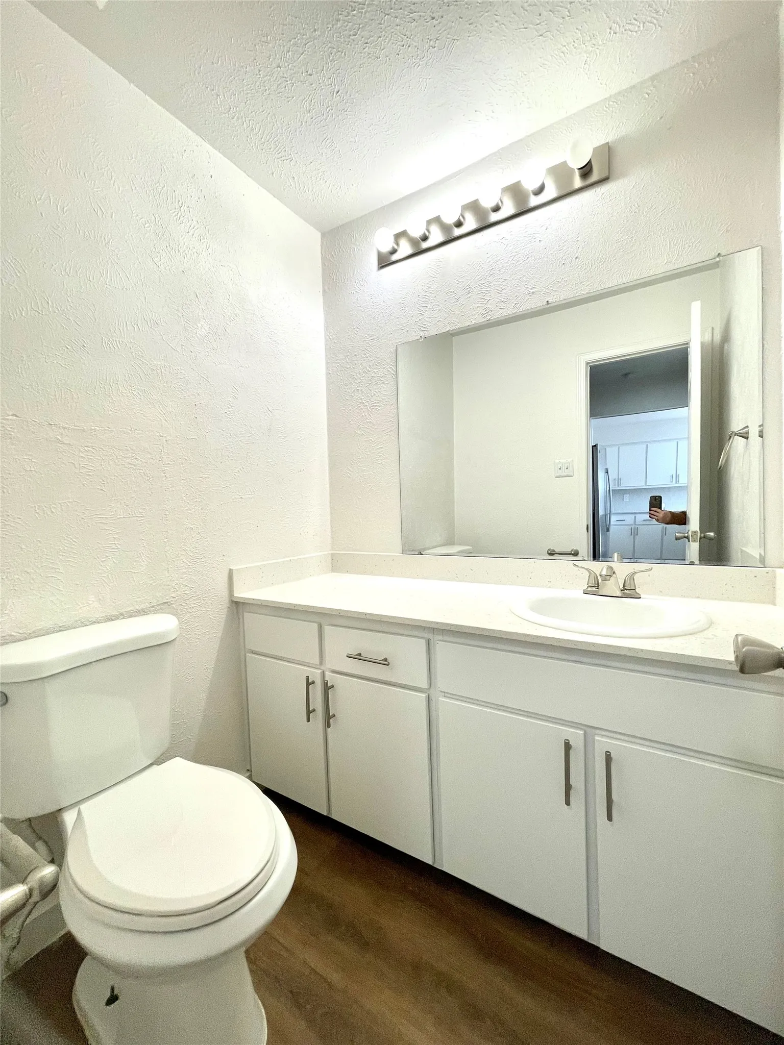 Bathroom featuring a textured ceiling, toilet, vanity, and hardwood / wood-style flooring