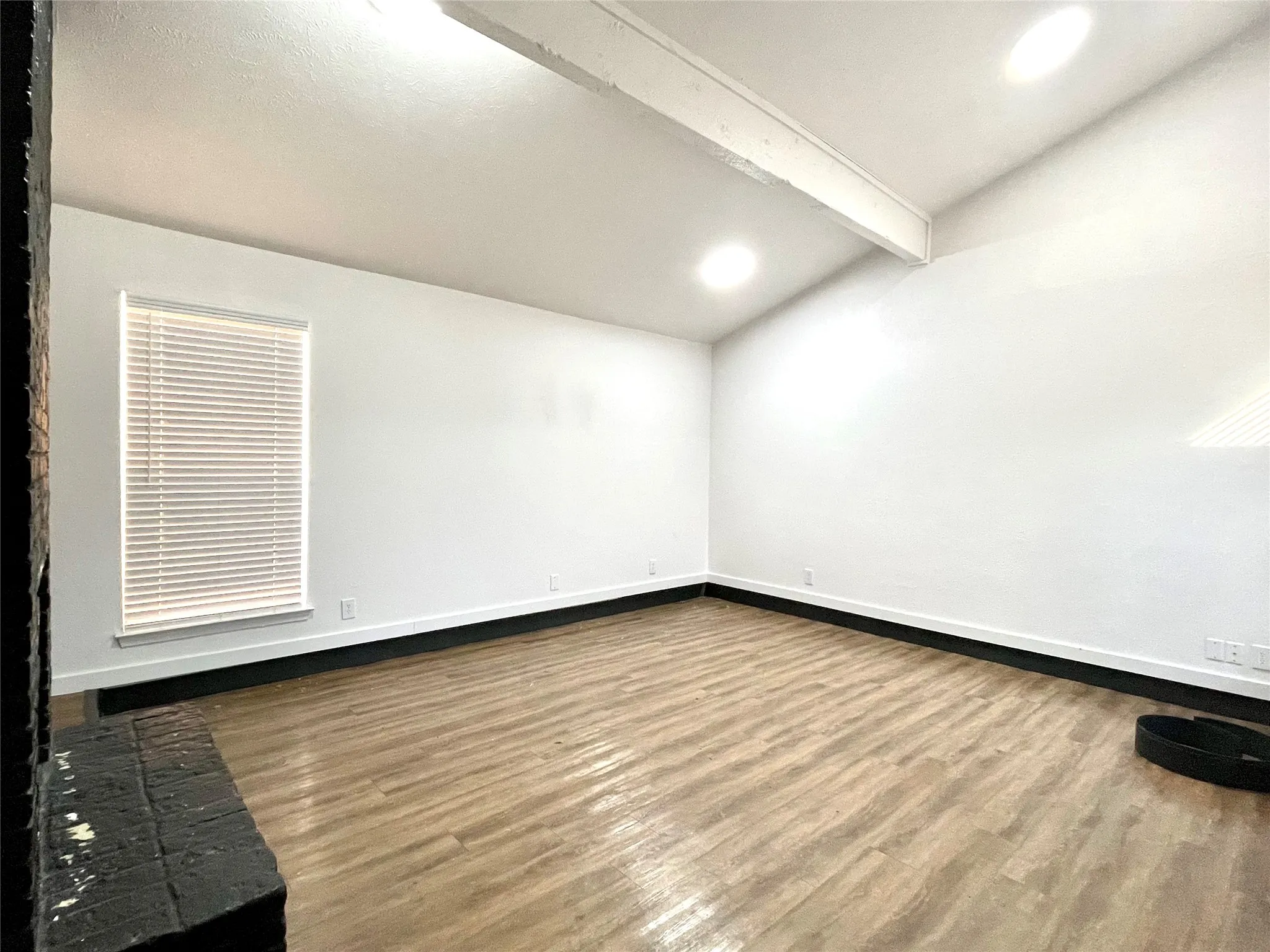 Unfurnished room with hardwood / wood-style floors and vaulted ceiling with beams